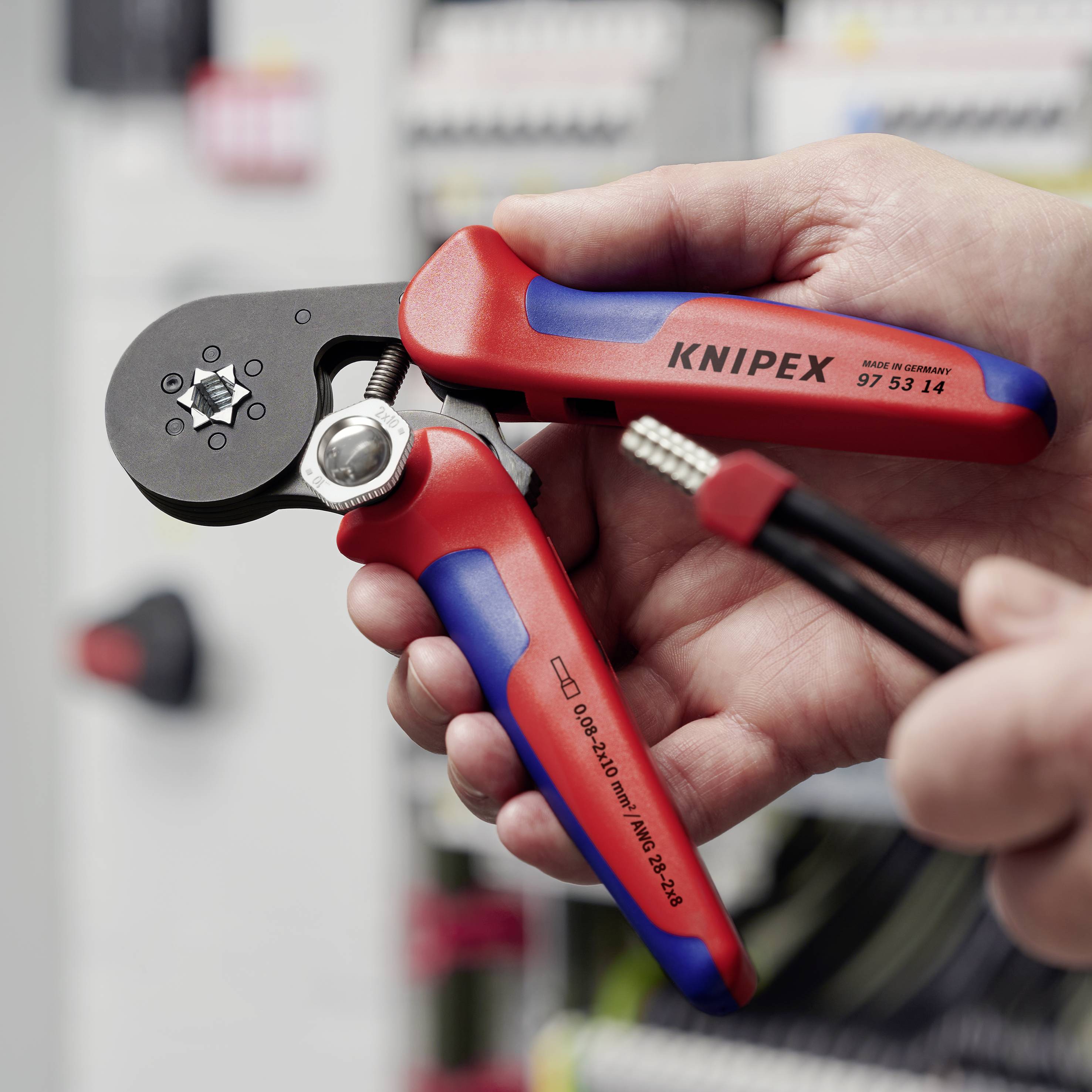 „Ein Paar rote Crimpzangen der Marke Knipex wird in der Hand gehalten, bereit zum Quetschen eines Kabels.“