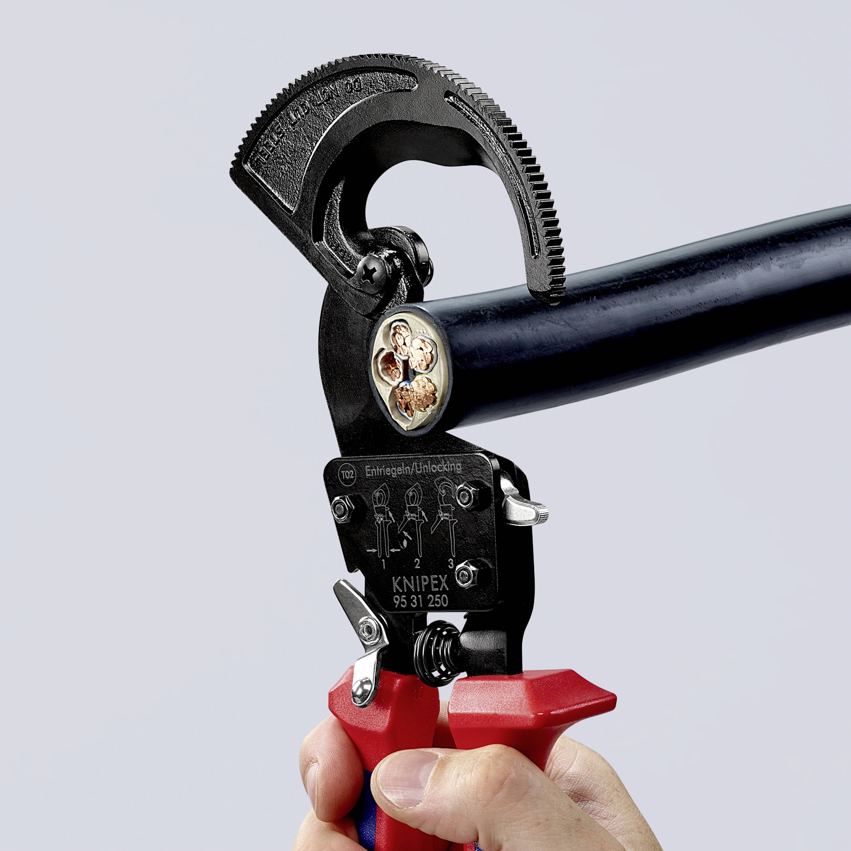 Eine Hand hält einen KNIPEX-Kabelschneider, der ein dickes schwarzes Kabel schneidet. Das Kabel zeigt Innenleiter und Abschirmung.