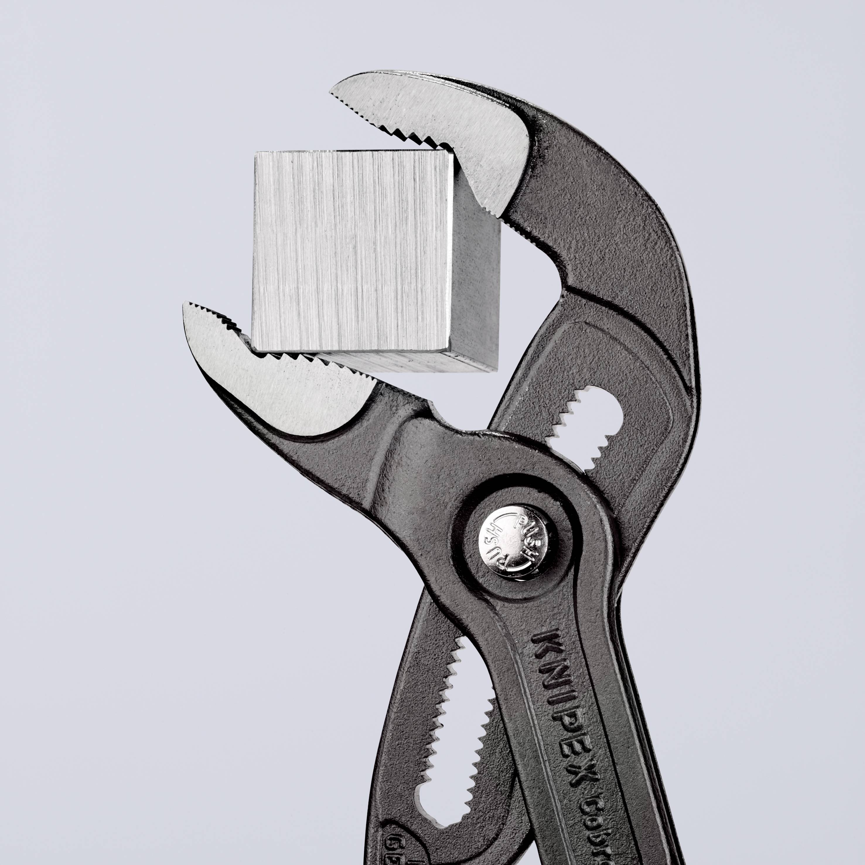 Eine verstellbare Zange hält einen Metallwürfel; symbolisiert Präzision und Kontrolle bei der Handhabung von Materialien.