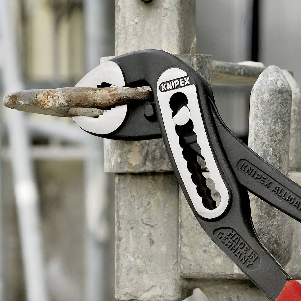 Zange der Marke Knipex hält einen rostigen Nagel in einem Metallgitter.