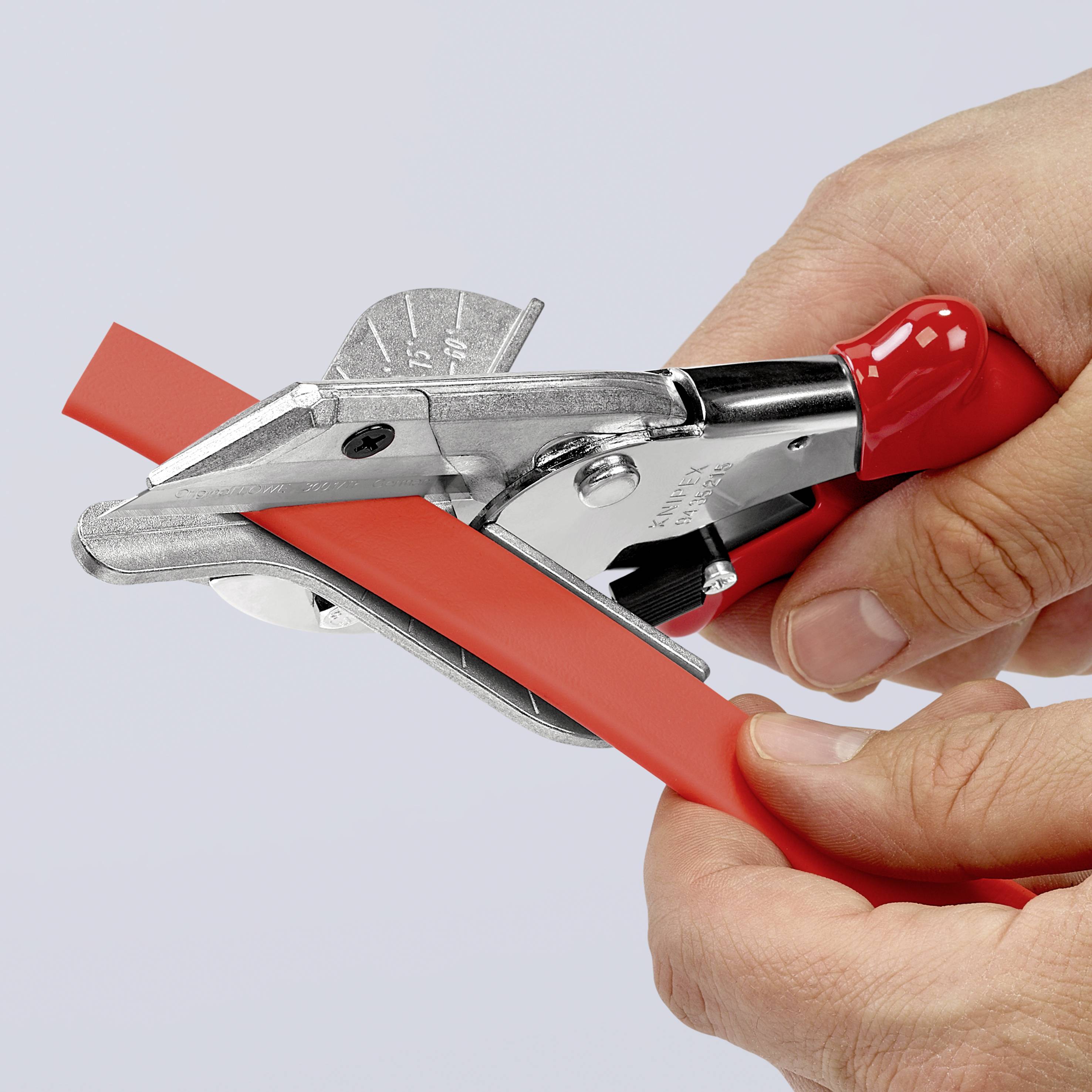 Eine Person schneidet ein rotes Kabel mit einem Kabelschneider ab. Der Kabelschneider hat einen roten Griff und eine silberne Klinge.