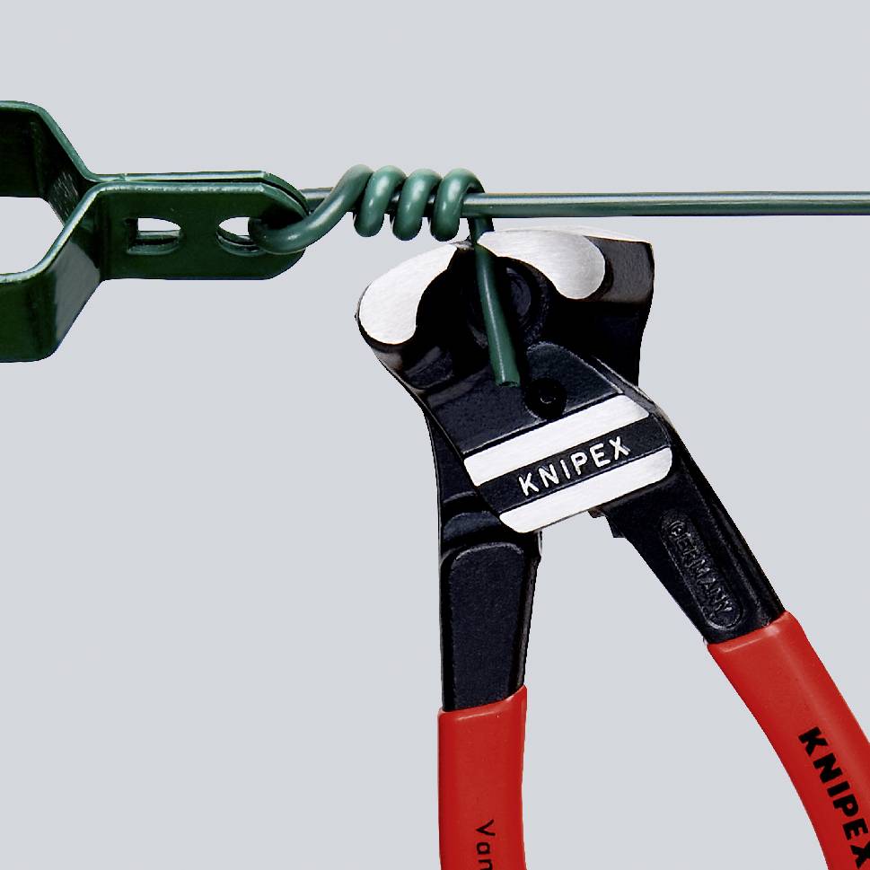 Eine KNIPEX Zange schneidet einen grünen Draht, der mit einer grünen Kralle fixiert ist. Die Zange hat rote Griffe.