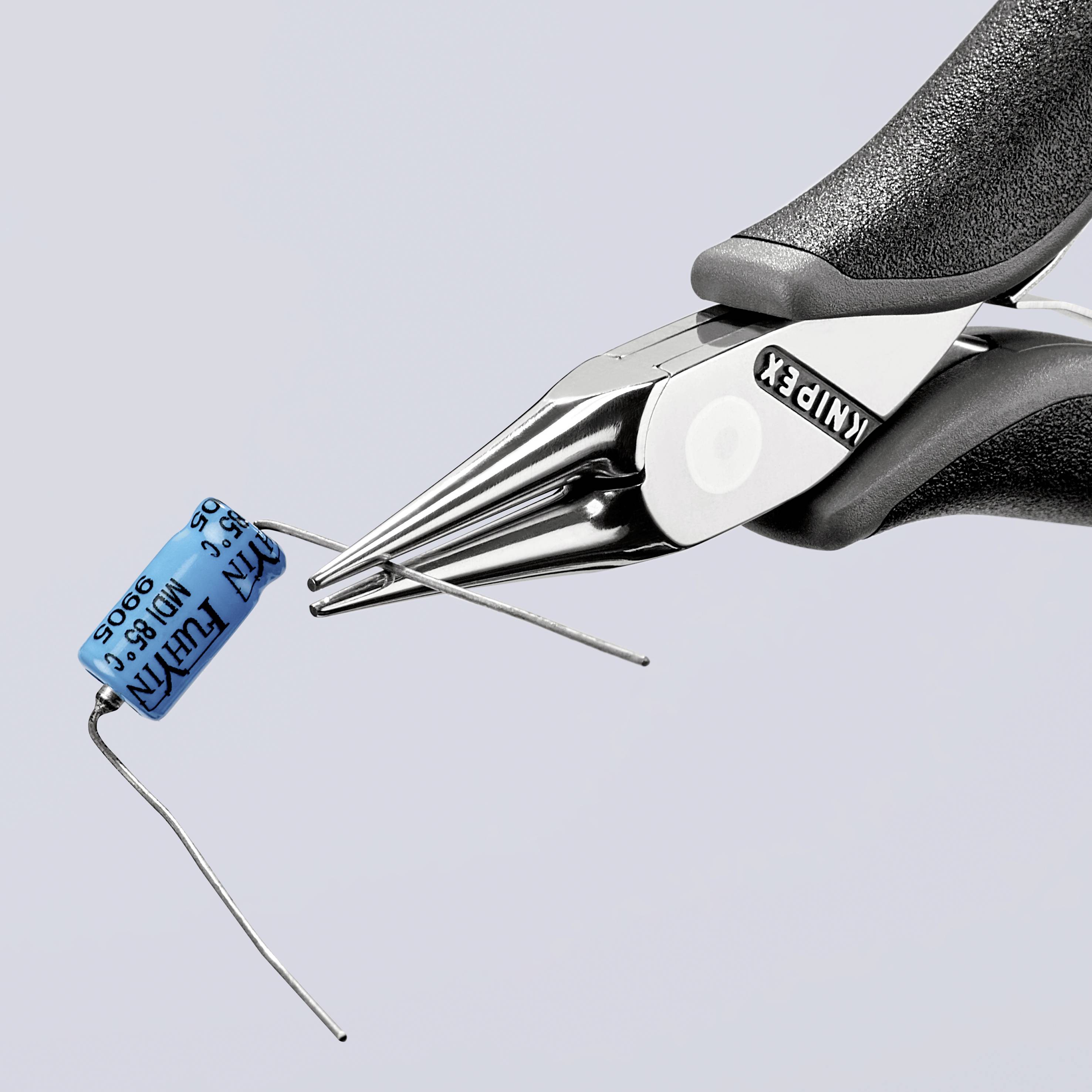 Eine Zange hält einen blauen Elektrolytkondensator. Die Zange ist silbern und hat schwarze Griffe, die Marke ist sichtbar.