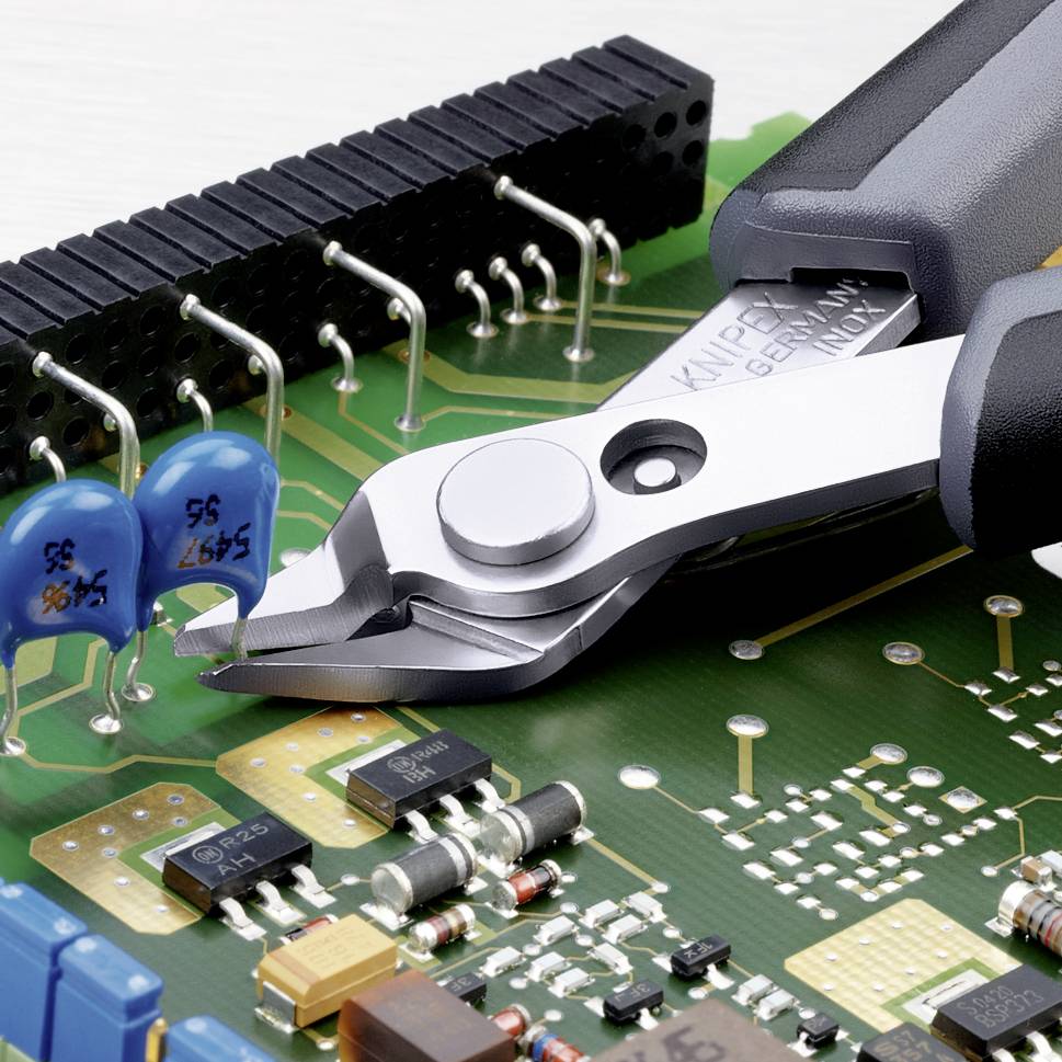 Ein Paar Seitenschneider schneidet einen Draht auf einer mit elektronischen Bauteilen bestückten Leiterplatte.