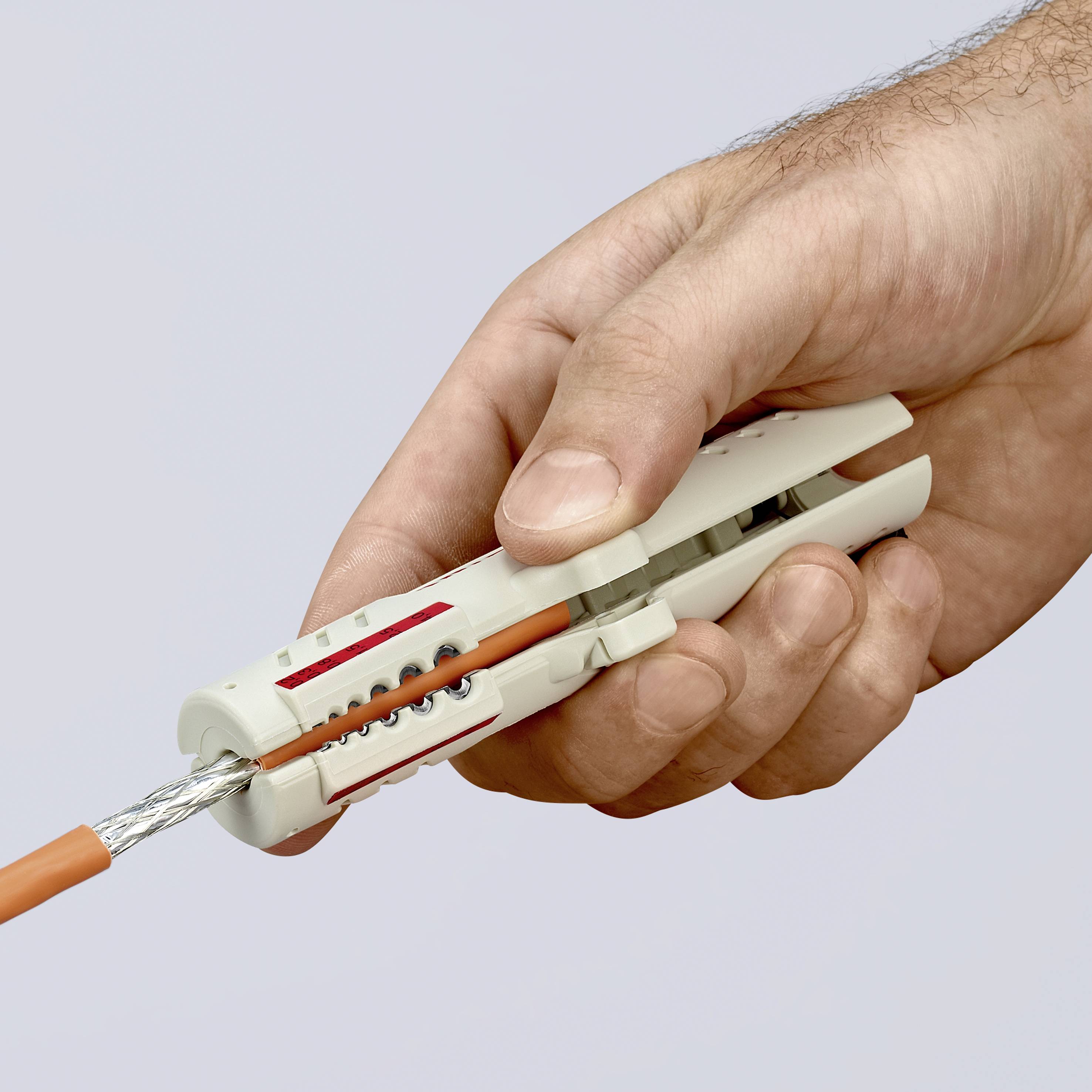 Eine Hand hält einen grauen Kabelschneider, der ein orangefarbenes Kabel schneidet.