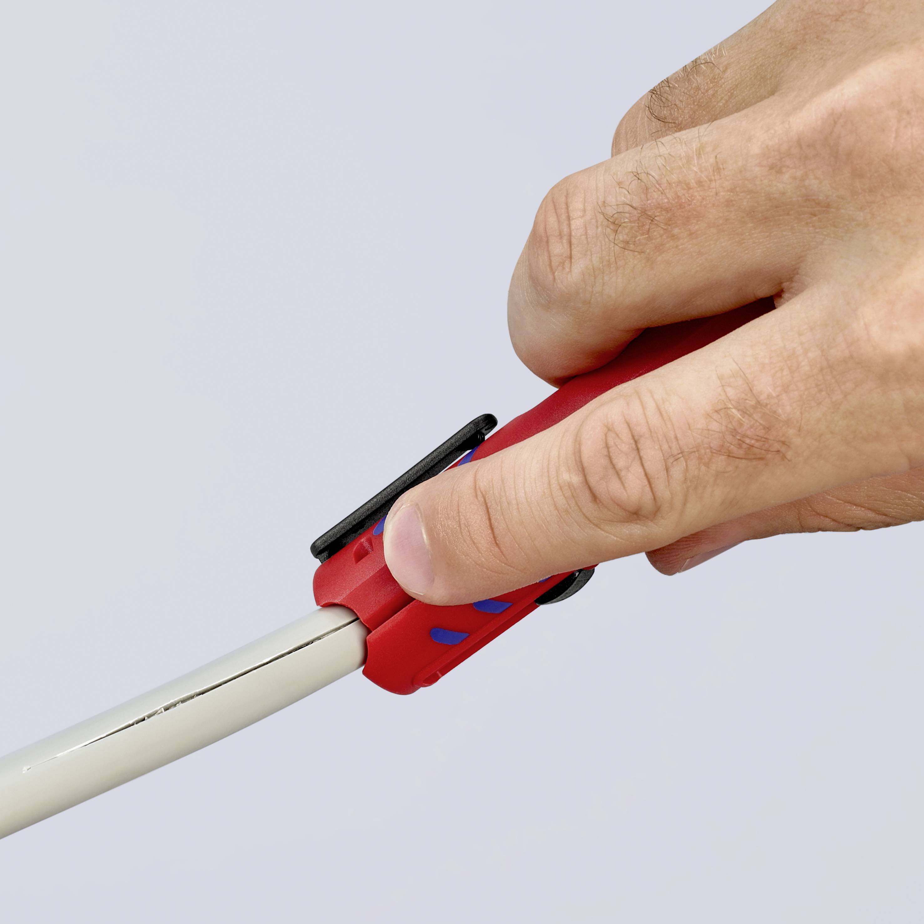 Eine Hand betätigt einen Cutter, um ein kabelähnliches Objekt zu schneiden. Der Fokus liegt auf dem Griff und der Klinge des Werkzeugs.
