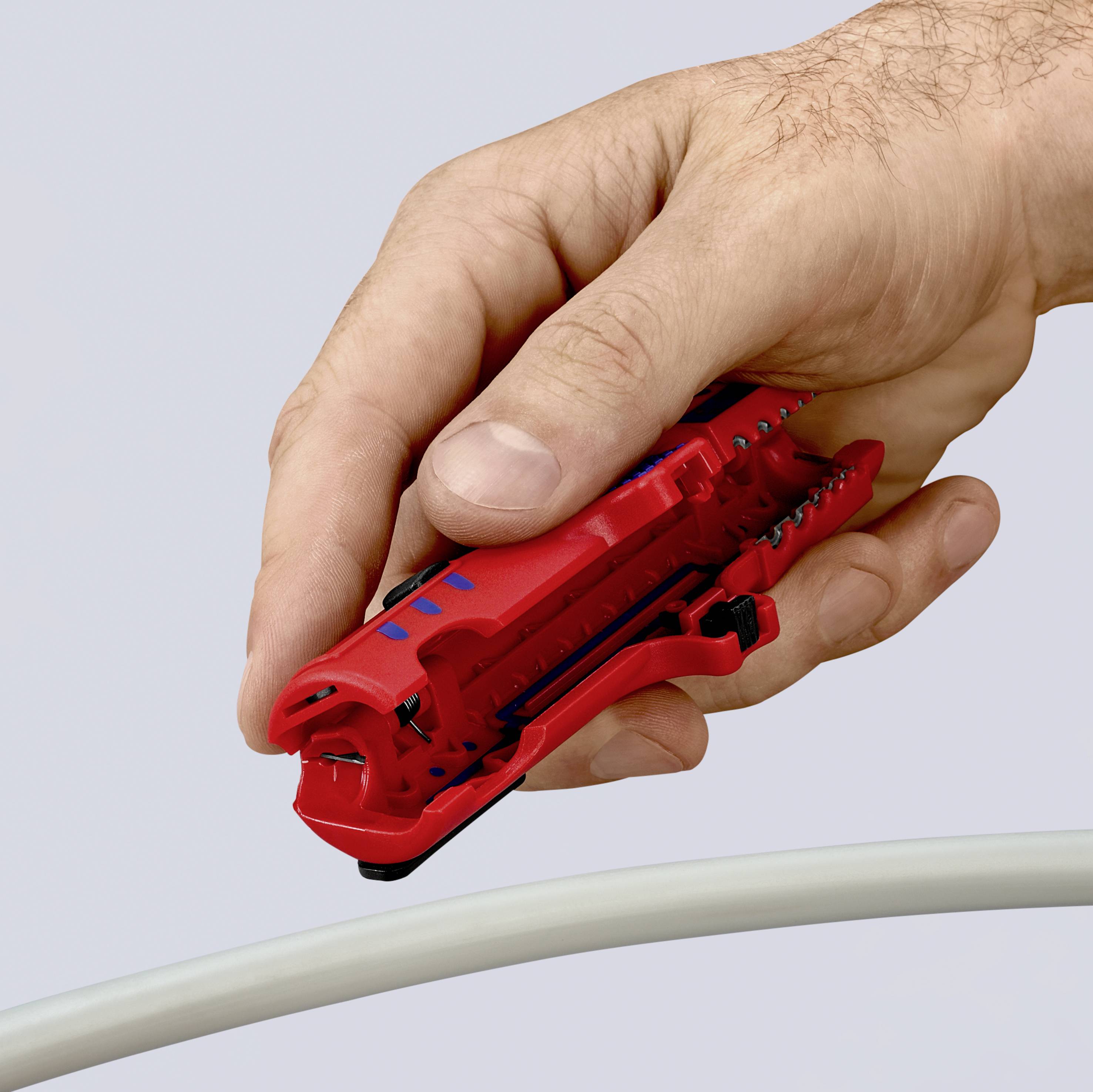 Hand benutzt ein rotes Kabelschneidewerkzeug, um ein weißes Kabel zu bearbeiten.