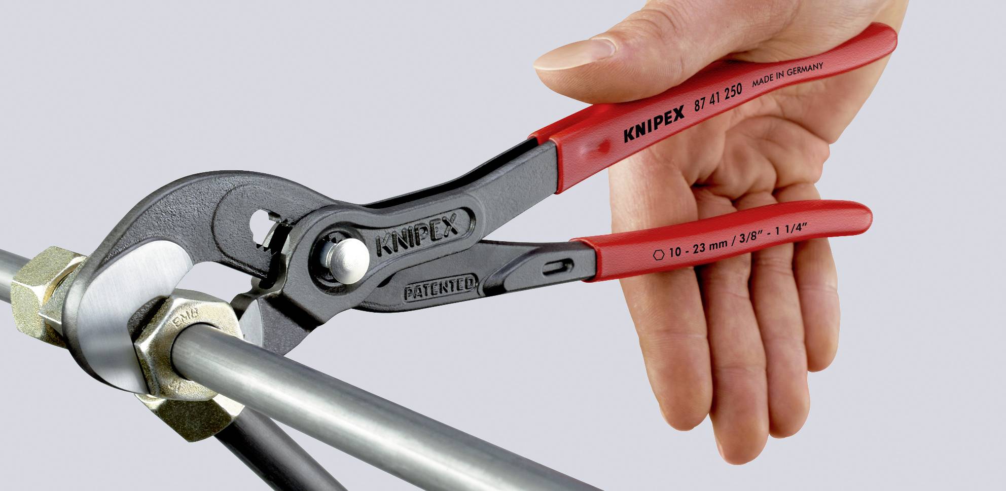 Rote Rohrzange greift Rohr an Anschlussmutter, gehalten von einer Hand. Werkzeug aus Stahl mit ergonomischen Griffen.