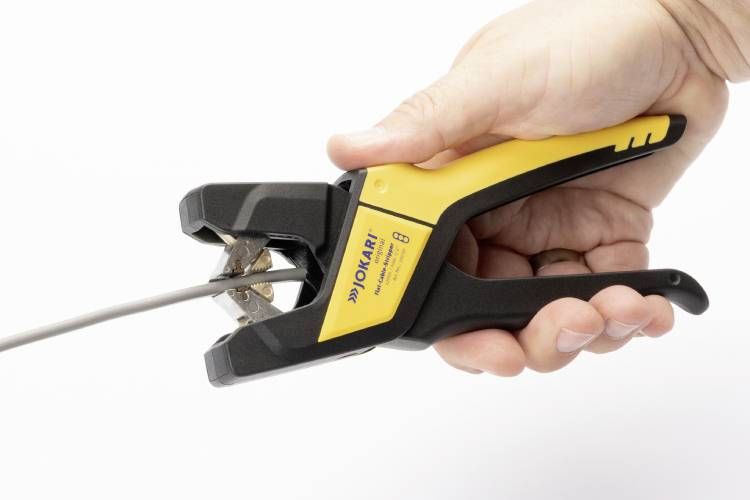 Jemand hält einen entmantelnden Seitenschneider in der Hand, der ein Kabel greift. Das Werkzeug ist schwarz und gelb.