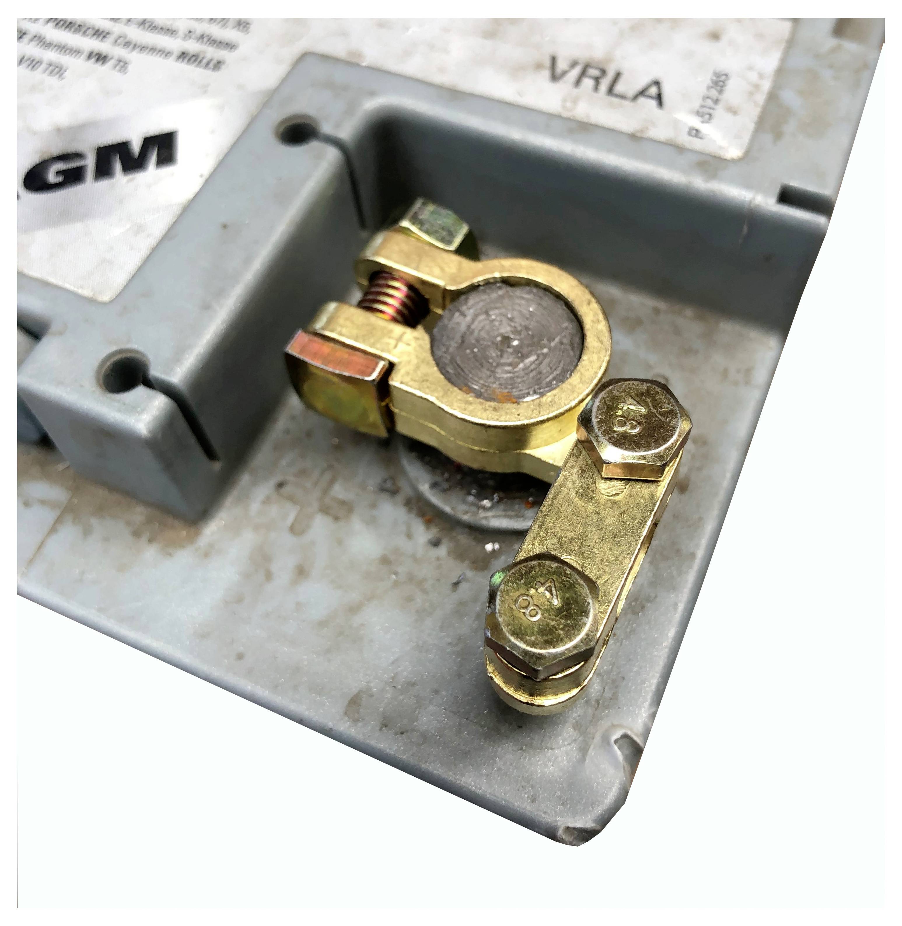 Eine Nahaufnahme eines Batterieklemmpols, der eine Messingklemme zeigt, die an dem Minuspol auf dem Batteriegehäuse befestigt ist.