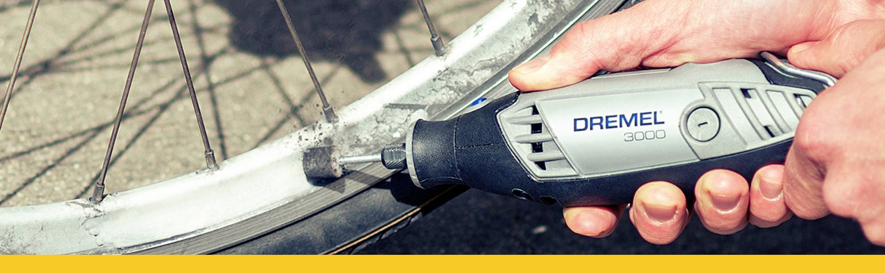 Eine Hand hält ein Dremel-Werkzeug und schleift den Rand eines Fahrradreifens ab.