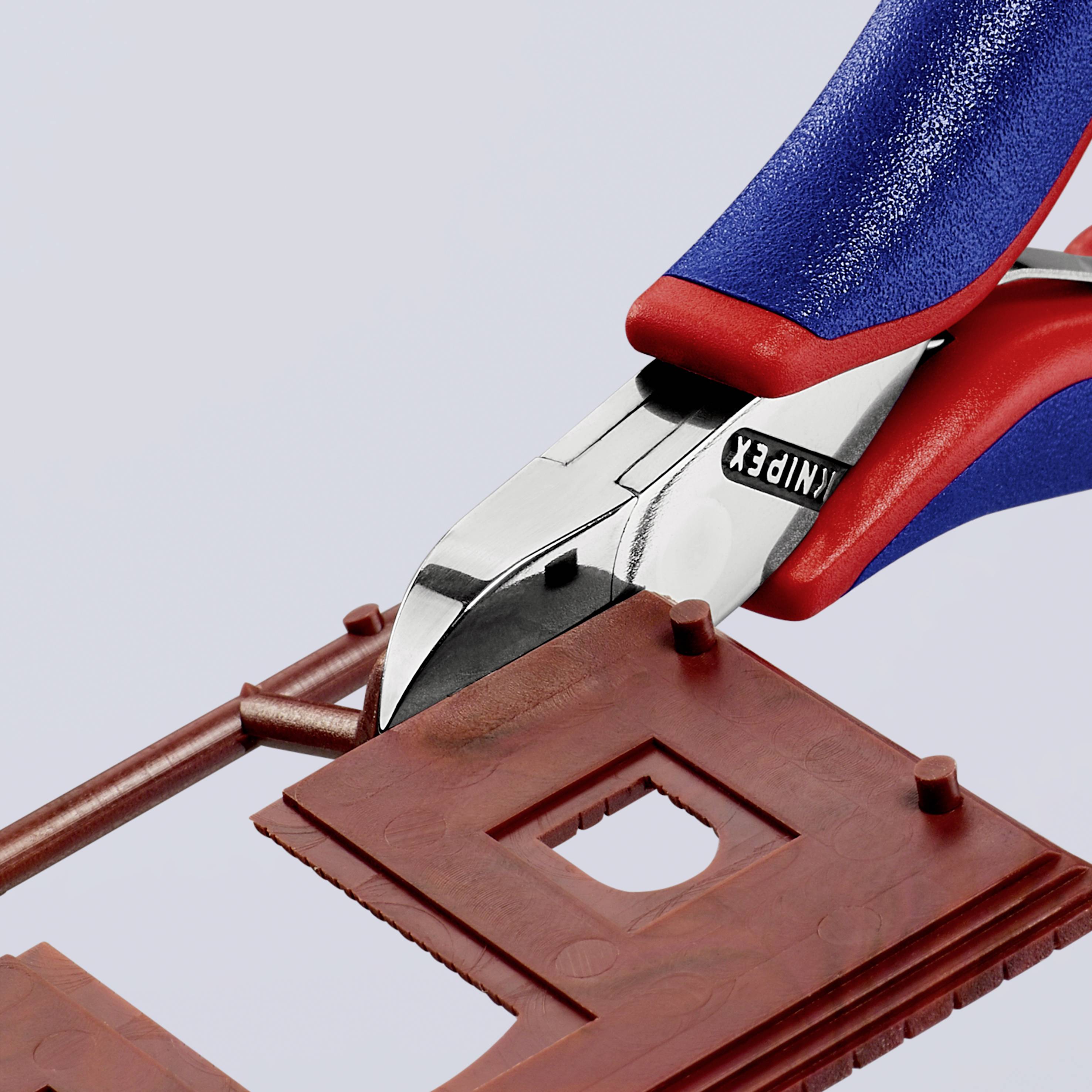 Eine rote Zange durchschneidet ein braunes, quadratisches Kunststoffteil. Der Markenname 'KNIPEX' ist auf der Zange sichtbar.