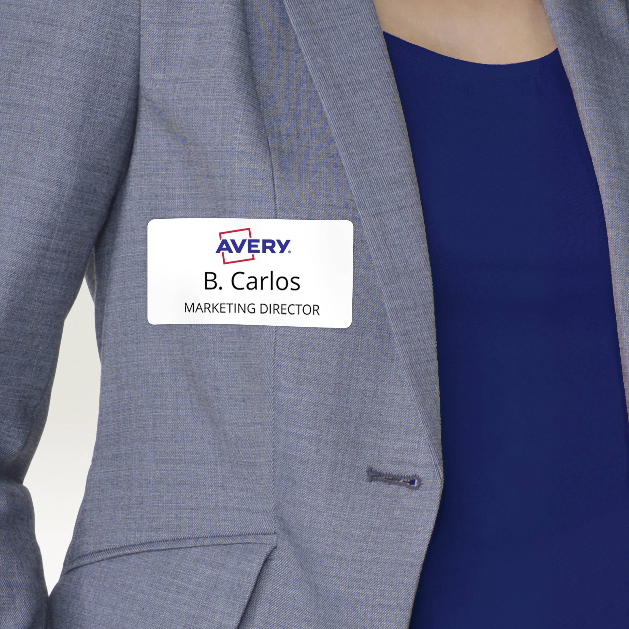 Person trägt einen grauen Blazer mit einem Namensschild. Das Schild zeigt 'B. Carlos, Marketing Director'.