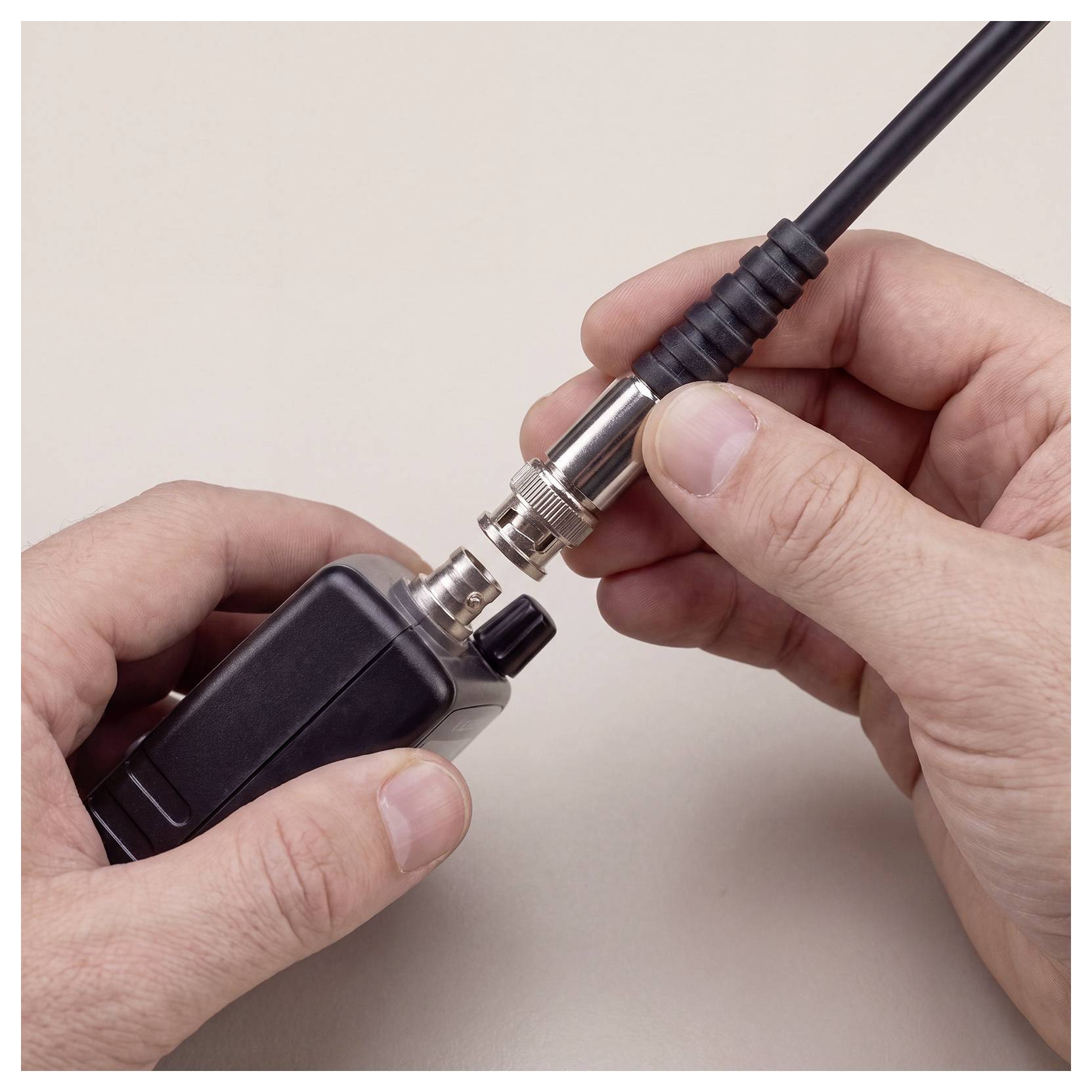 Hände, die ein Koaxialkabel an einen schwarzen elektronischen Gerätestecker anschließen.
