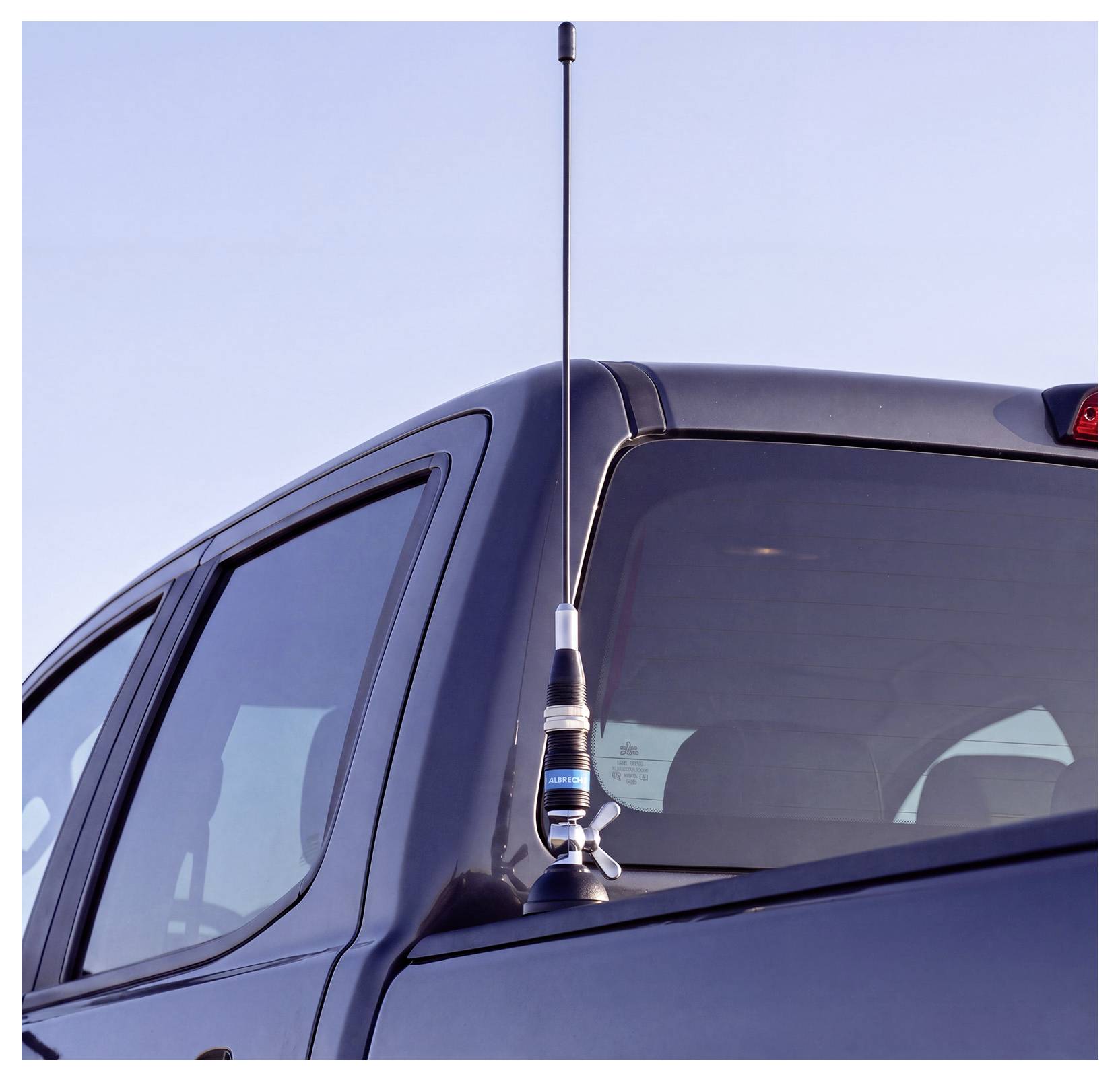 Hohe Antenne auf dem Dach eines dunklen Pickup-Trucks gegen einen klaren Himmel montiert.