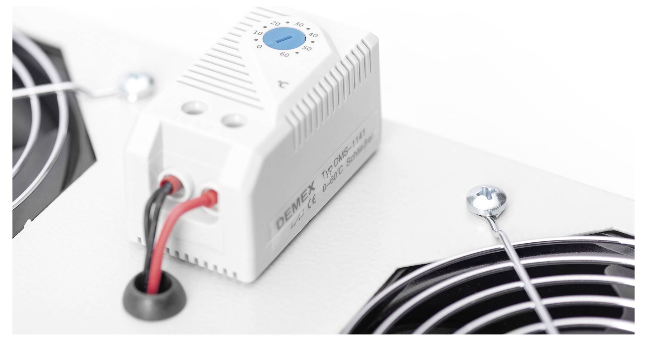 Eine Nahaufnahme eines elektronischen Geräts, das mit roten und schwarzen Kabeln verbunden ist, über zwei Metallgebläseöffnungen auf weißem Hintergrund angebracht.