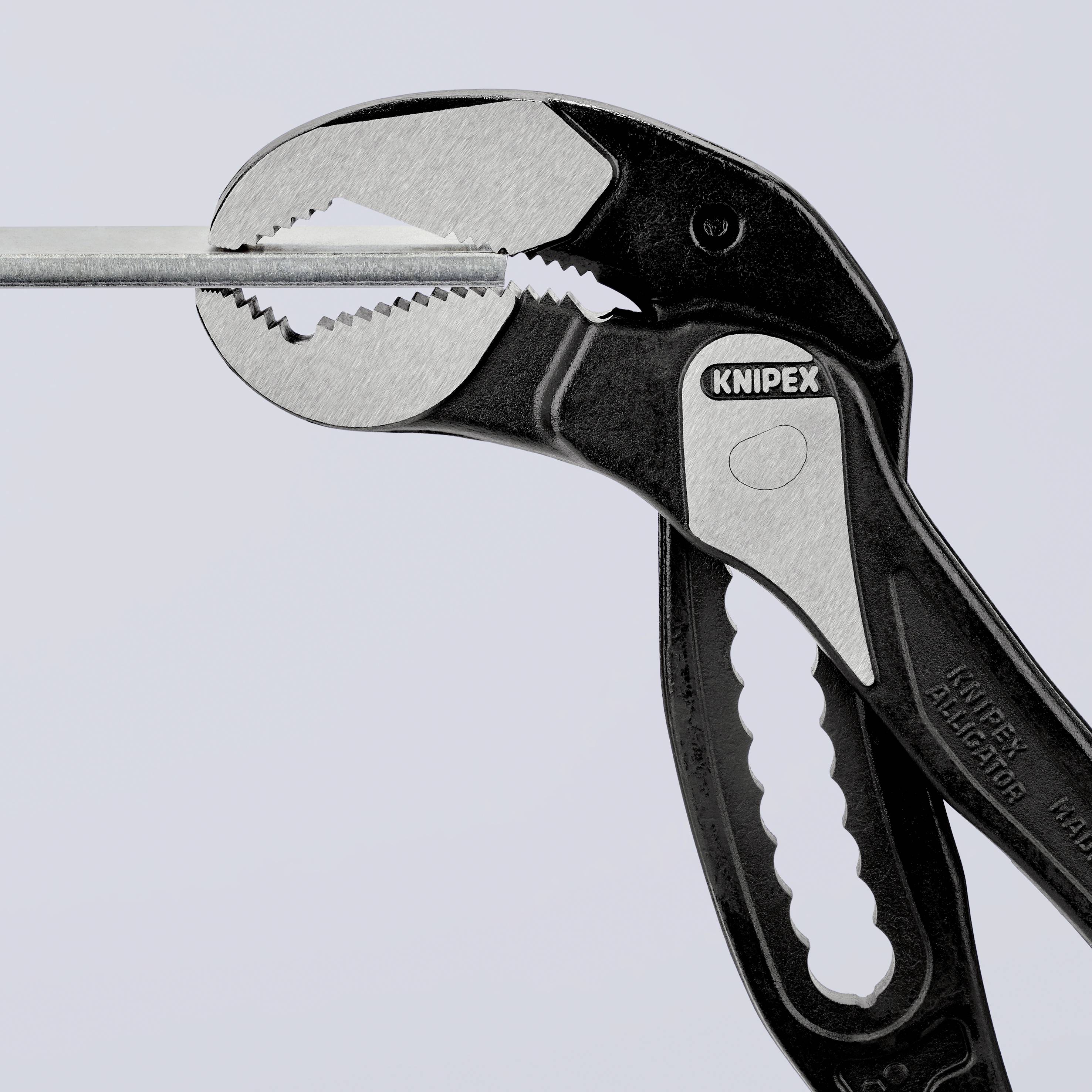 Zange mit schwarzem Griff und offener Backe hält Metallstück.