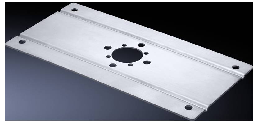 Metallplatte mit mehreren gebohrten Löchern, darunter ein großes zentrales Loch, umgeben von kleineren Löchern, auf dunklem Hintergrund.