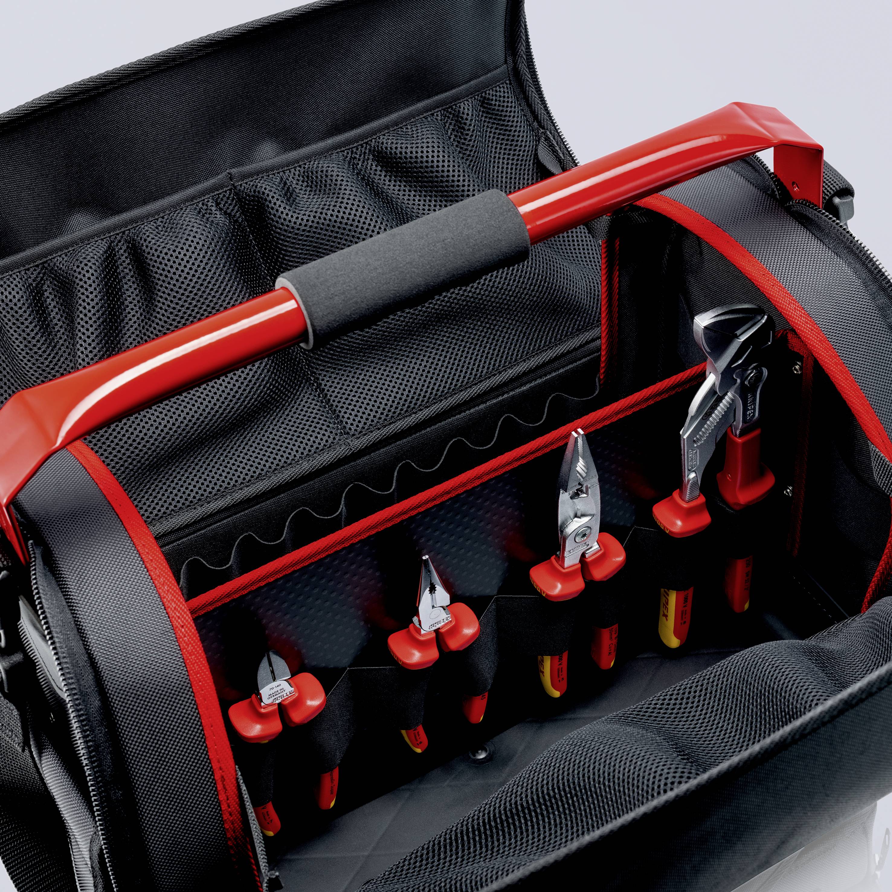 Eine Werkzeugtasche mit roten Griffen und mehreren Fächern, die Schraubendreher, Zangen und einen Schraubenschlüssel enthält.