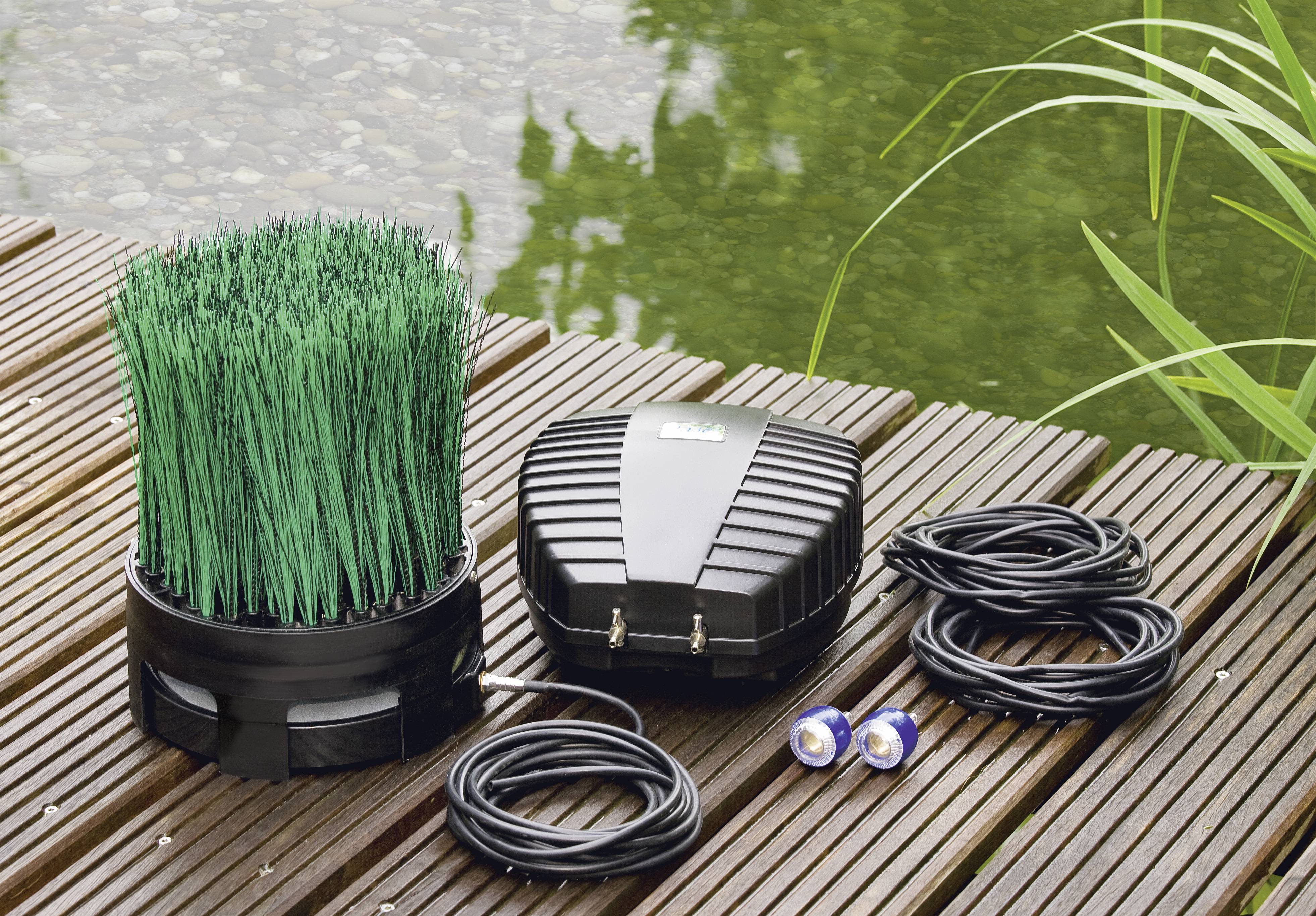 Aquatische Garten-Belüftungsanlage auf Holzdeck, inklusive grasartigem Diffusor, Pumpe und Schlauch neben einem Teich.