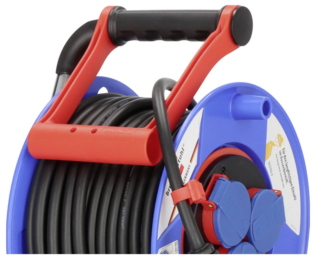 Eine blaue Kabelrolle mit einem roten Griff, aufgewickelt mit schwarzem Elektrokabel und ausgestattet mit mehreren blauen Steckdosen an der Seite.