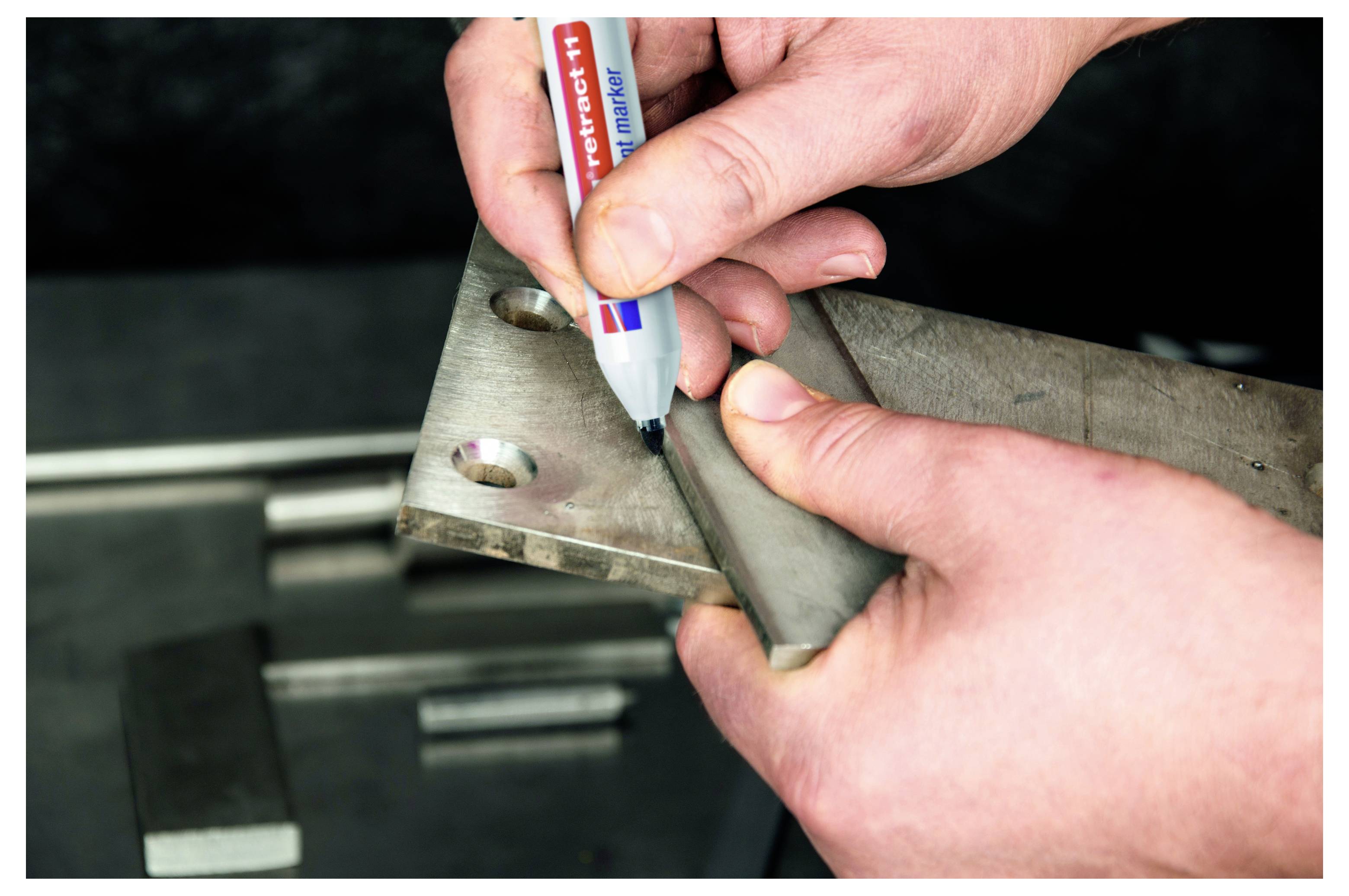 Hände, die mit einem Marker eine Metallhalterung markieren, wahrscheinlich beim Messen oder Planen eines Schnitts in einer Werkstatt.
