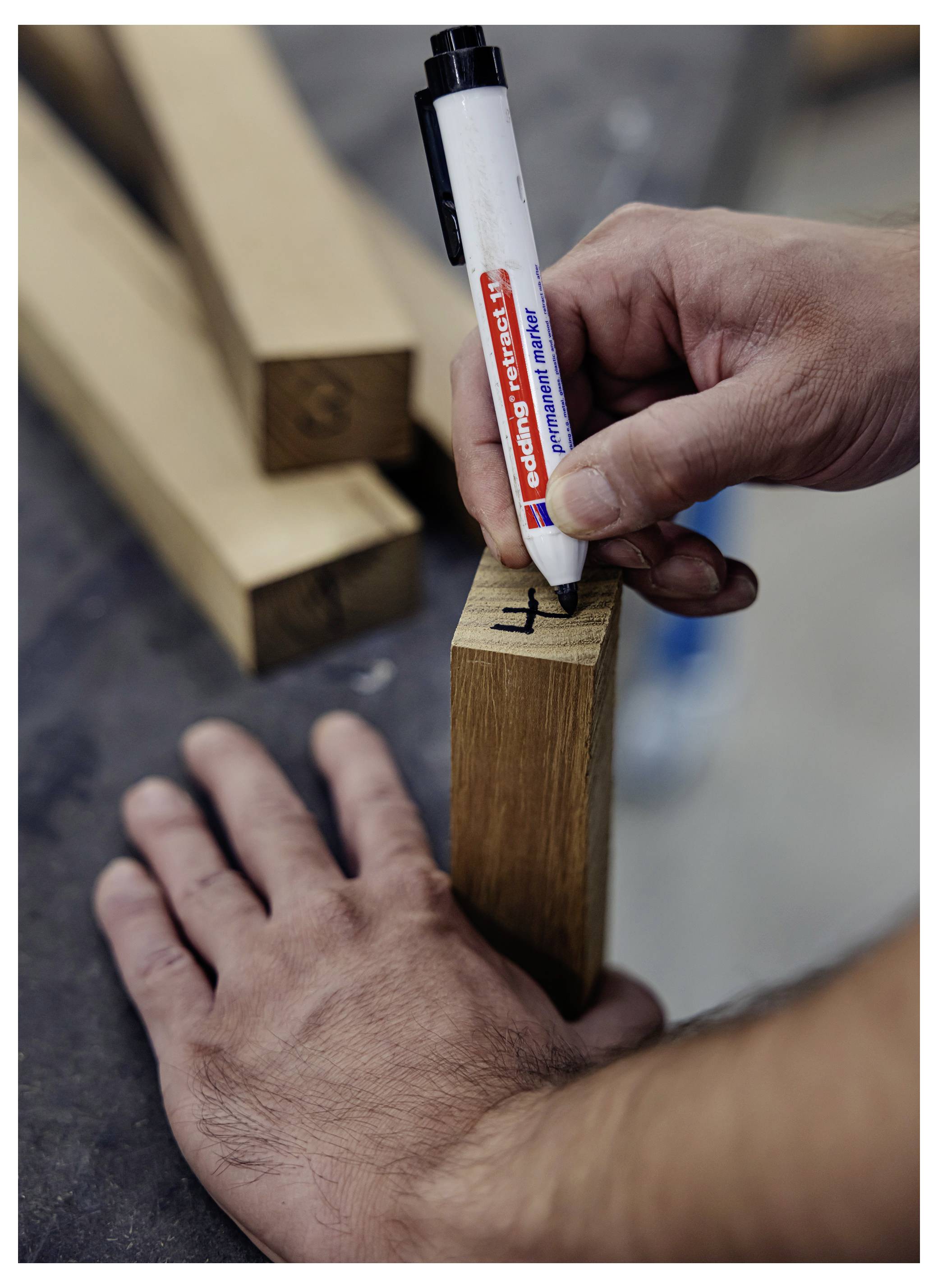 Mit einem weißen Konstruktionsmarker eine Markierung auf einem Holzbrett in einer Werkstatt anbringen, die eine Messung oder Schnittlinie anzeigt.