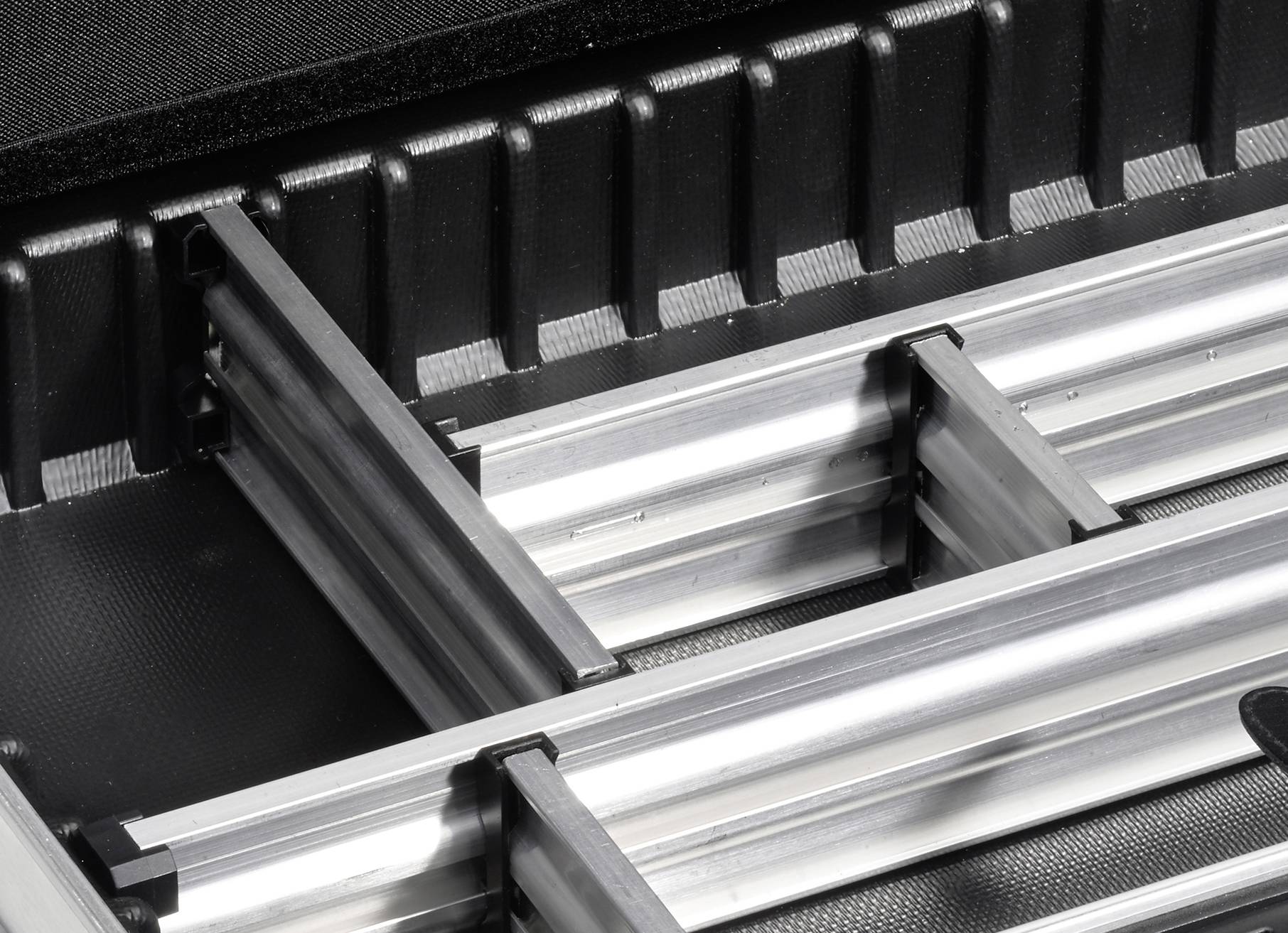 Aluminiumprofile in einer strukturierten schwarzen Box, die zur sicheren Aufbewahrung und zum Transport von Bauteilen dient.