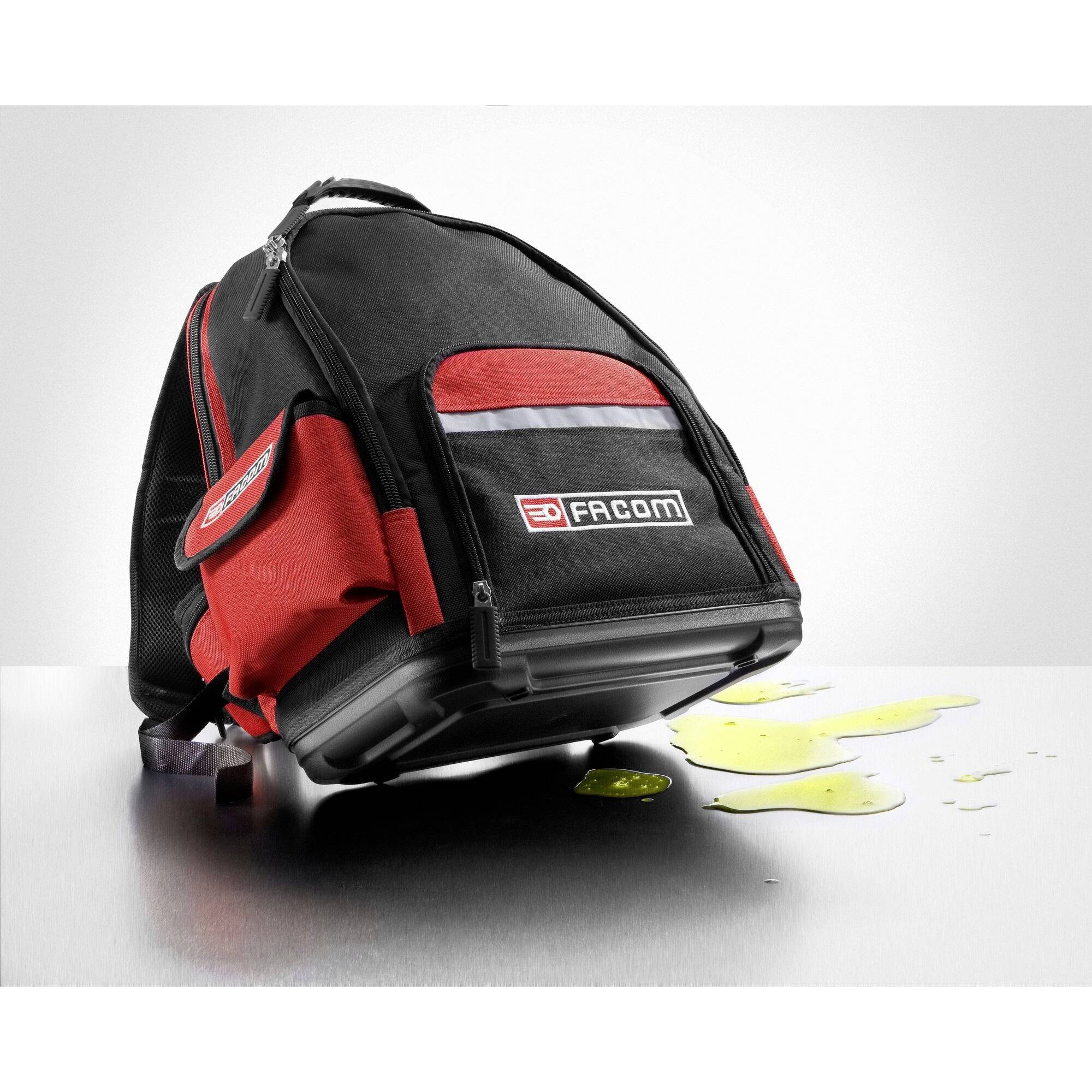 Ein schwarzer und roter Werkzeugrucksack steht auf einem Tisch mit einer gelben Flüssigkeit daneben.