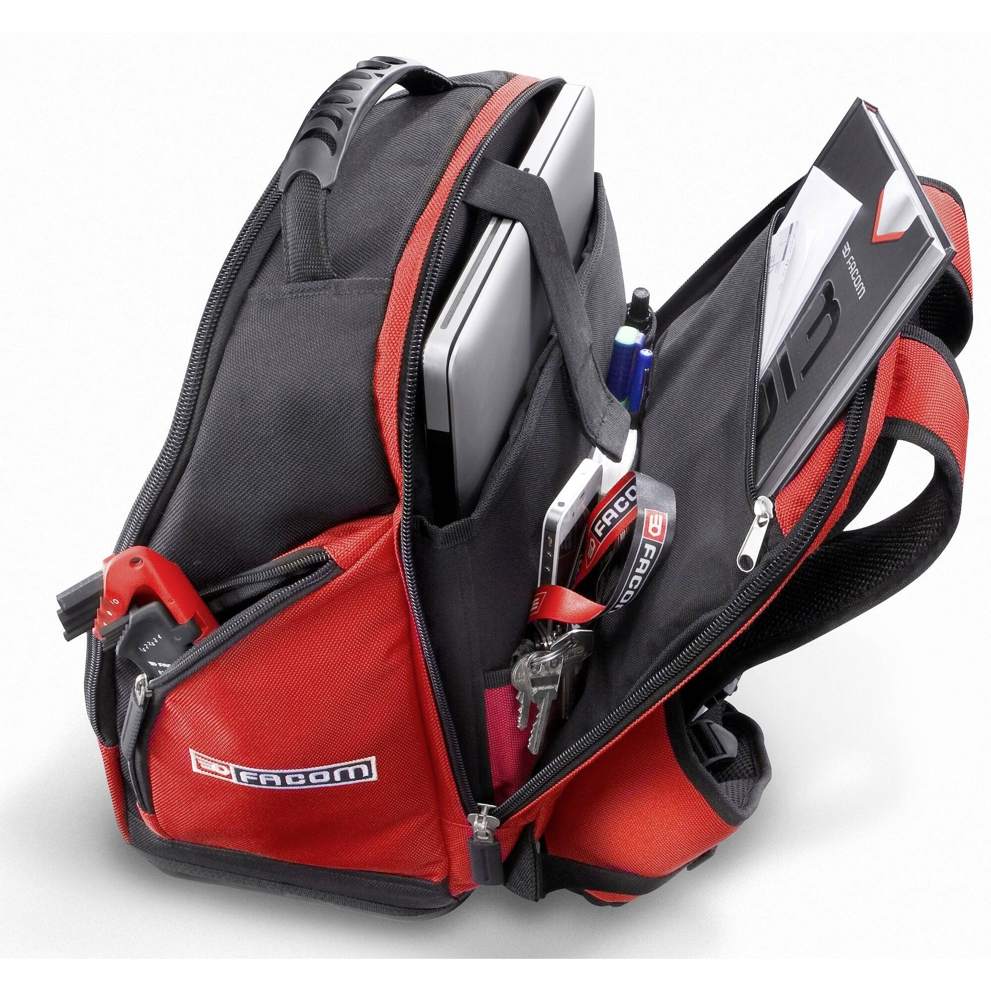 Ein geöffneter Rucksack mit einem Laptop, einem Heft, Stiften und Schlüsseln darin, alles gut organisiert in separaten Fächern.