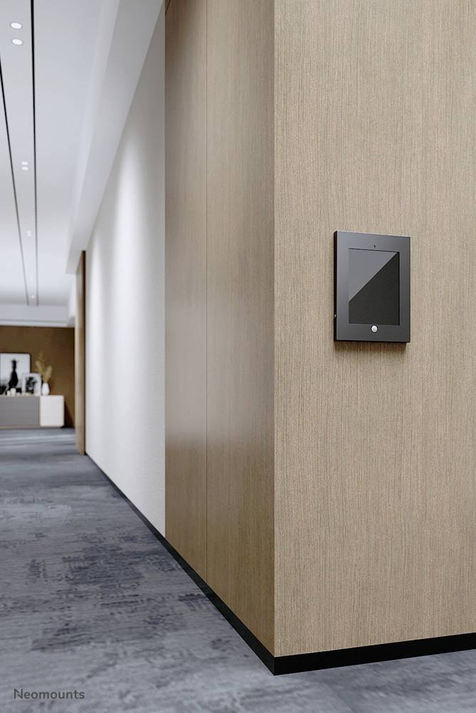 Ein Tablet ist an einer Holzwand in einem modernen Büroflur montiert. Im Hintergrund sind vage Büromöbel zu erkennen.