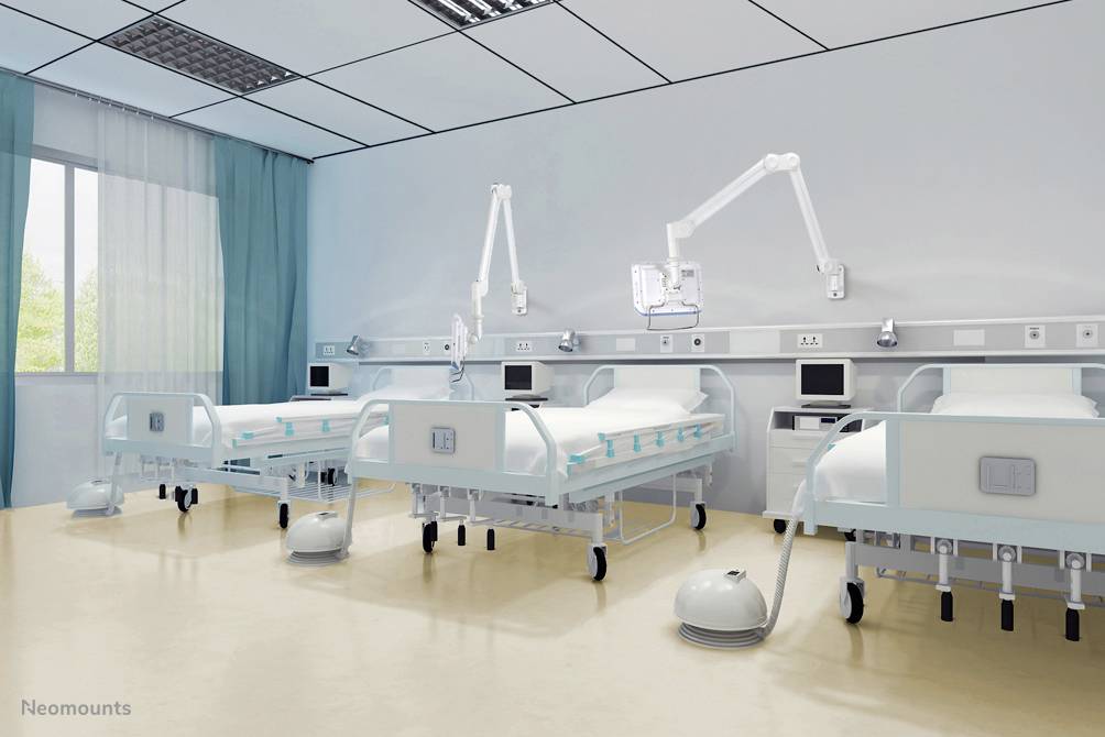 Zwei leere Krankenhausbetten in einem hellen, modernen Patientenzimmer mit medizinischen Geräten und Monitoren an den Wänden.