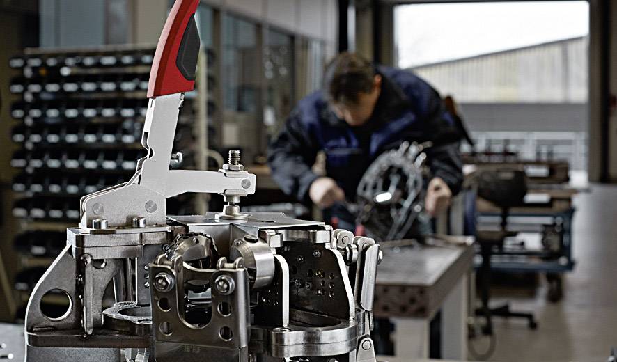 Maschine im Vordergrund in einer Werkstatt. Handwerker im Hintergrund, unscharf. Fokus auf Ingenieurarbeit und Maschinenbau.