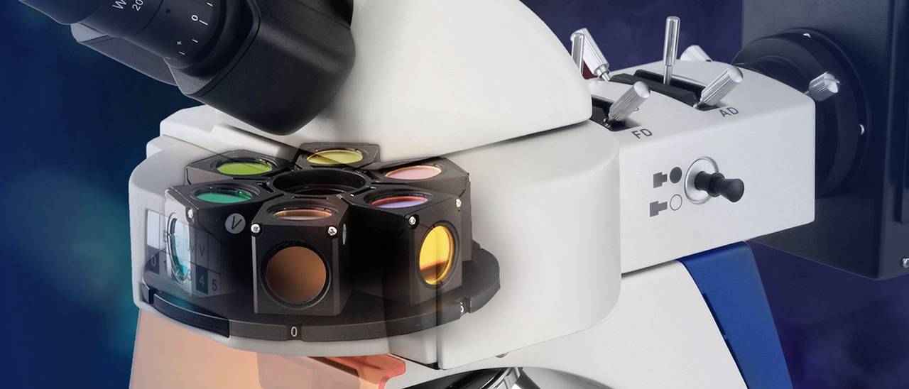 Mikroskop mit mehreren Filtern, darunter gelbes Licht sichtbar. Hochtechnologisches Gerät zur Laboranalyse.