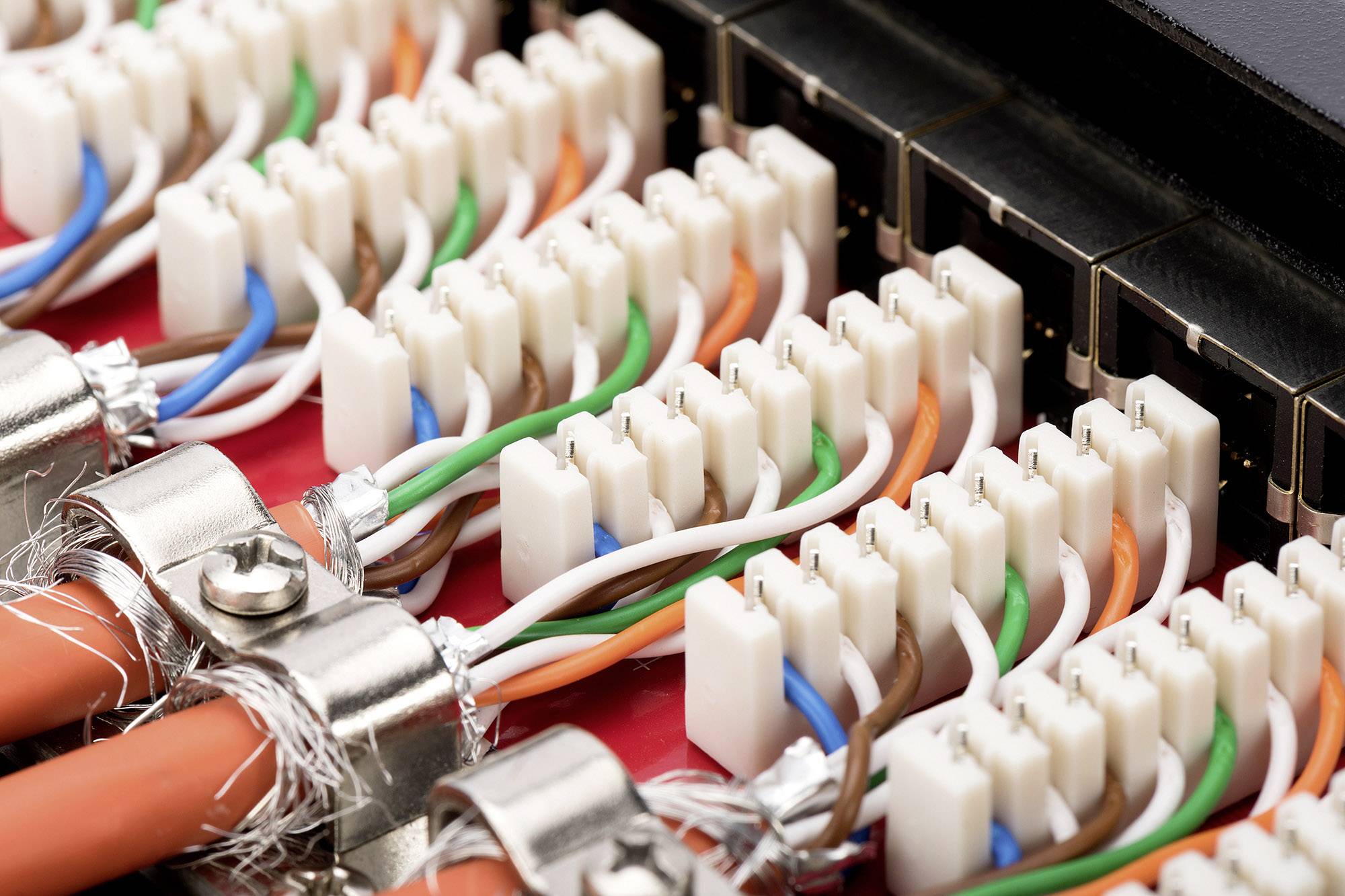 Nahaufnahme eines Netzwerkkabel-Panel mit bunten Ethernet-Kabeln, die in Anschlüsse eingesteckt sind.