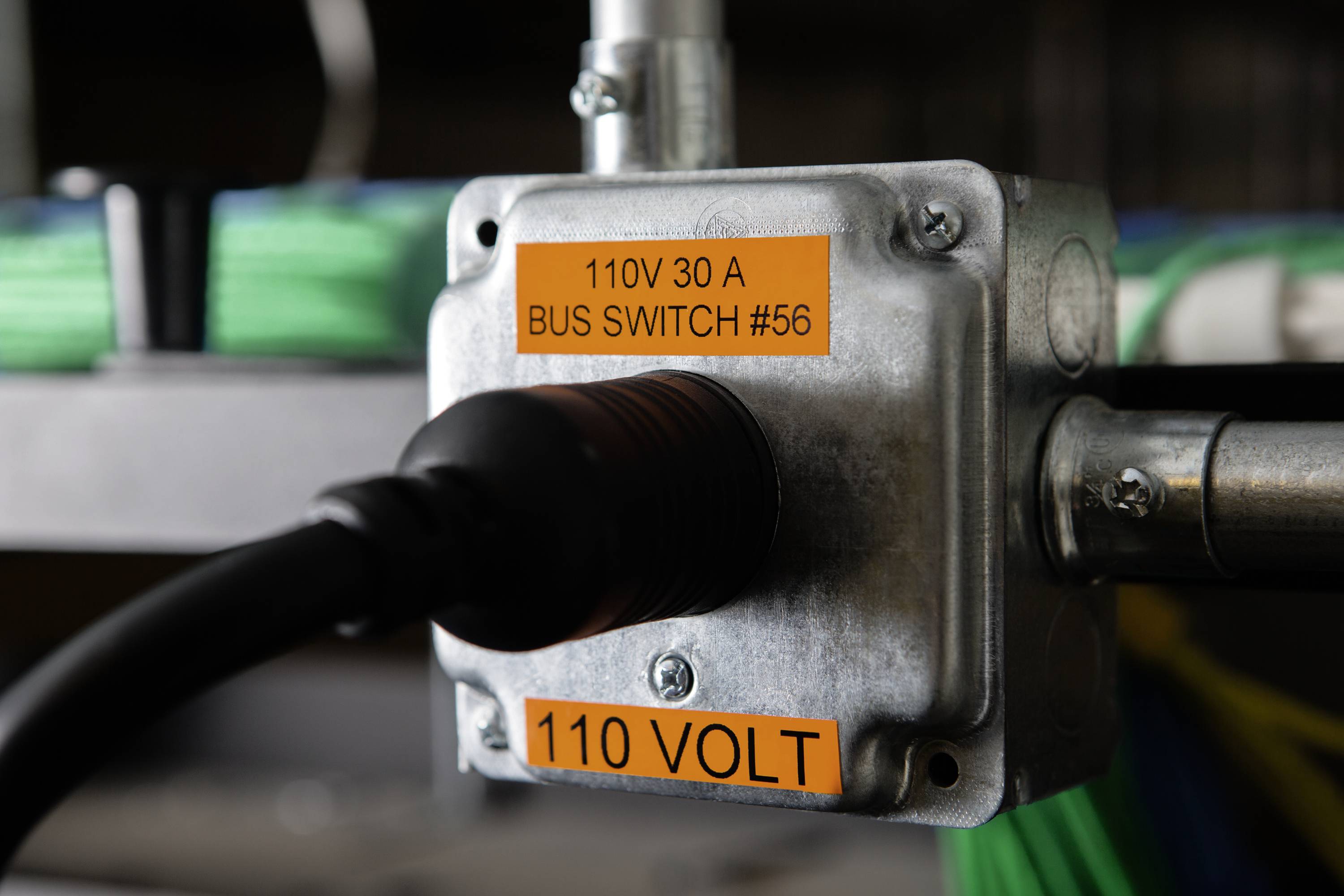 Metallkasten mit schwarzem Kabel; orange Aufkleber: '110V 30 A BUS SWITCH #56' und '110 VOLT'.