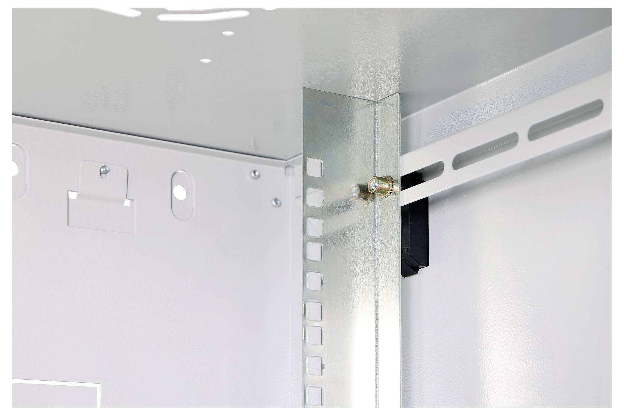 Das Bild zeigt die Innenecke eines Metallgehäuses für elektrische Komponenten mit einer geschlitzten Montageschiene und einem Eckbolzen, der Komponenten befestigt.