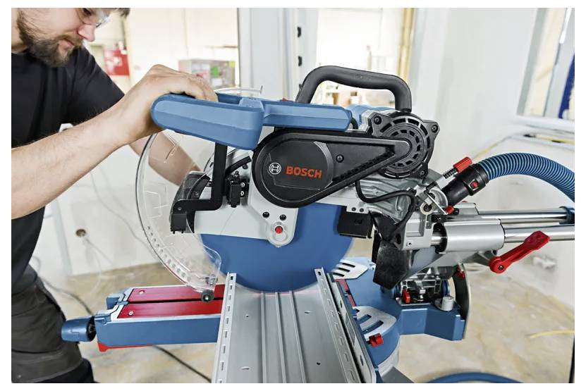 Ein Mann stellt eine Bosch-Gehrungssäge auf einer Werkbank ein und bereitet sich darauf vor, Material in einer Werkstatt zu schneiden.