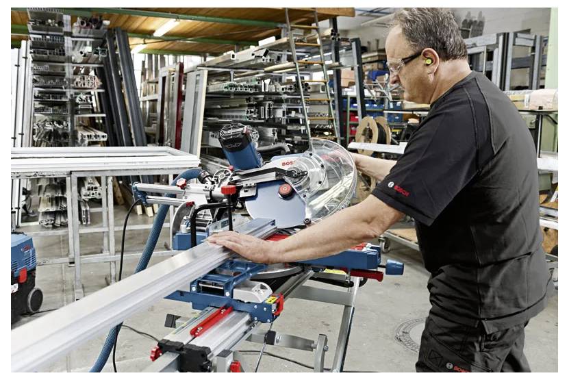 Hände, die einen Bosch-Fräser verwenden, der in einem Oberfräsentisch montiert ist, für Holzbearbeitung auf einer Holzwerkbank.