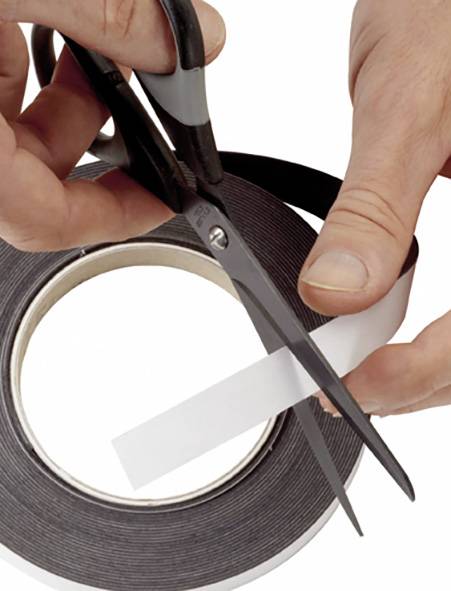 Eine Hand hält eine Schere, die ein Stück weißen Klebestreifen von einer Rolle abschneidet.