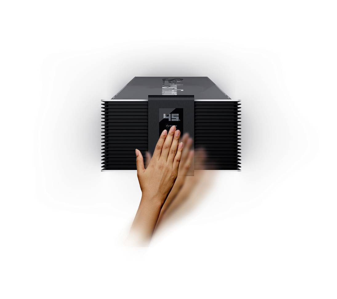 Die Bild zeigt eine schwarze elektronische Box; eine Hand wischt über die Front, um scheinbar eine digitale Anzeige zu bedienen.