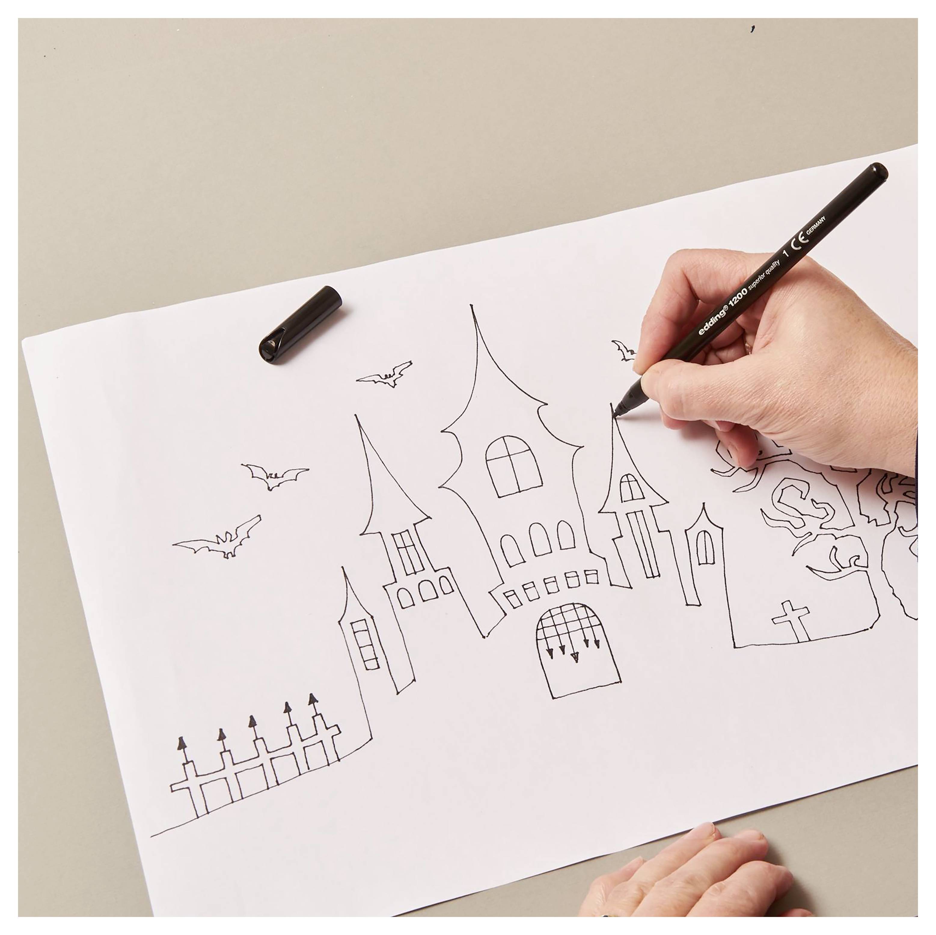 Handzeichnung eines gruseligen Spukhauses mit Fledermäusen auf Papier, mit schwarzem Stift umrissen von der Hand einer Person.