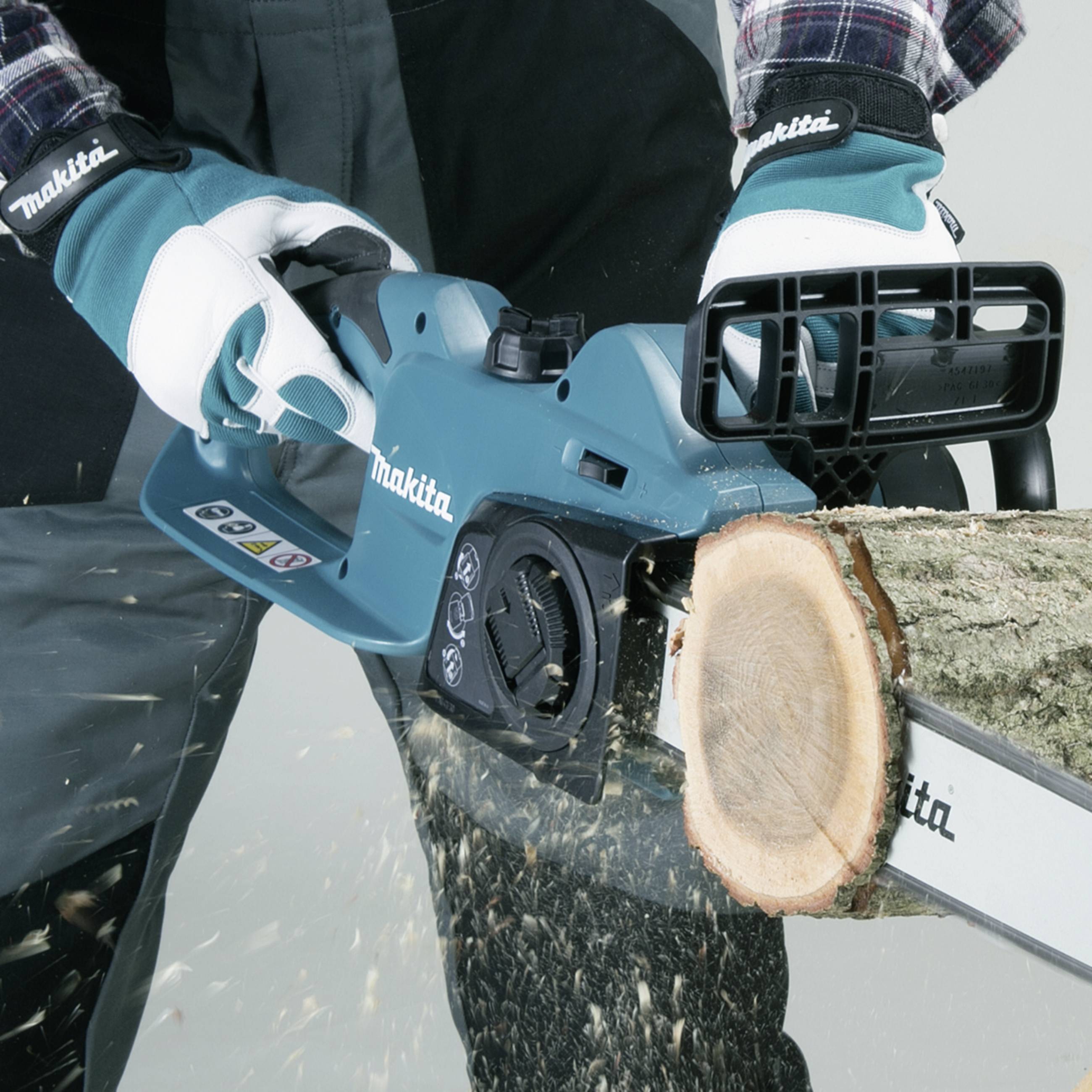Eine Person sägt mit einer blauen Kettensäge Holz. Die Kette schneidet durch einen Ast. Die Person trägt Arbeitshandschuhe.