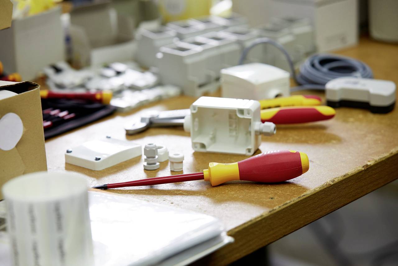 Werkzeug und Elektrozubehör auf einem Tisch, darunter Schraubendreher und Kabel. Vorbereitung für Elektroinstallationsarbeiten.