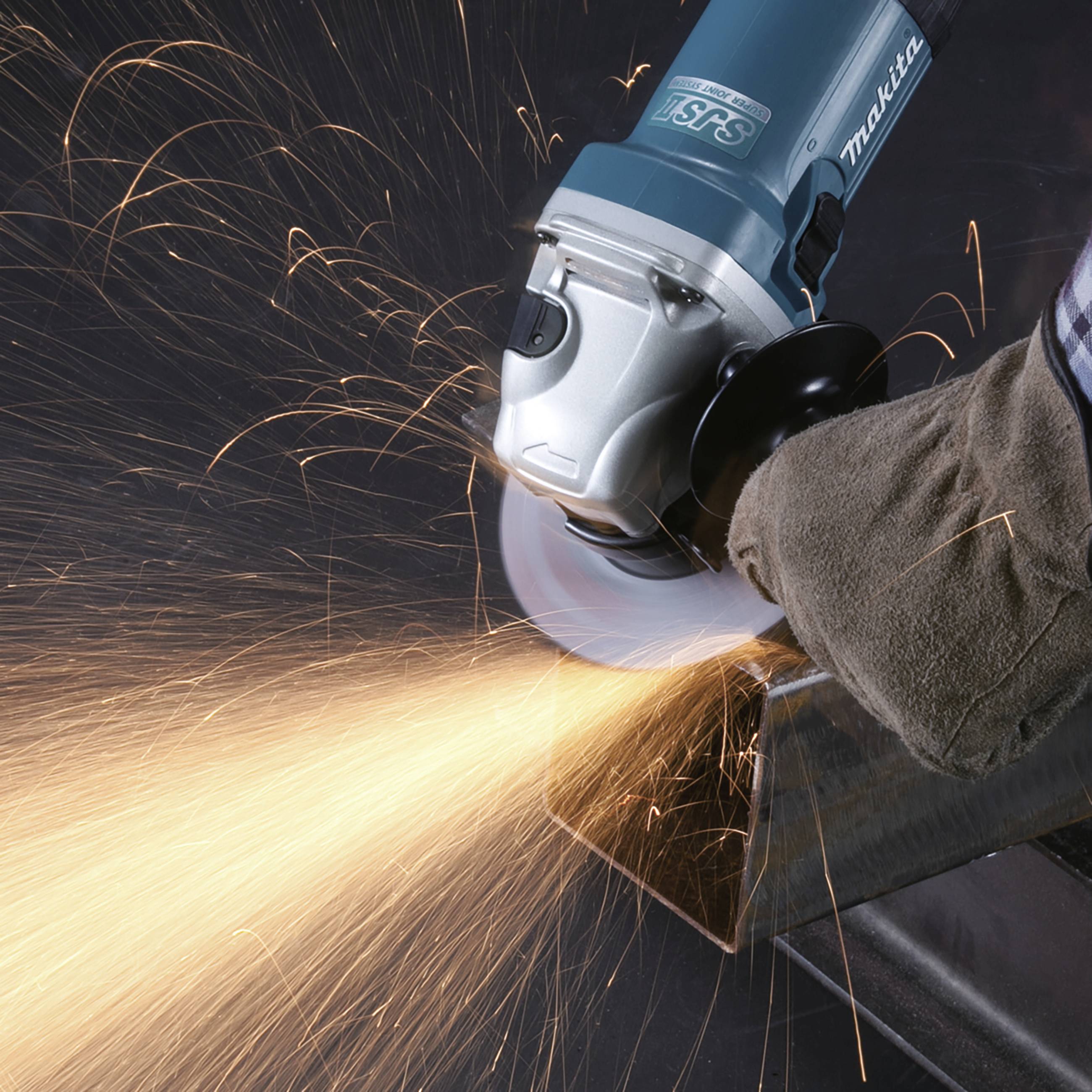 Eine Winkelschleifmaschine, die Funken sprüht, während sie Metall schleift. Die Maschine wird von einer behandschuhten Hand gehalten.