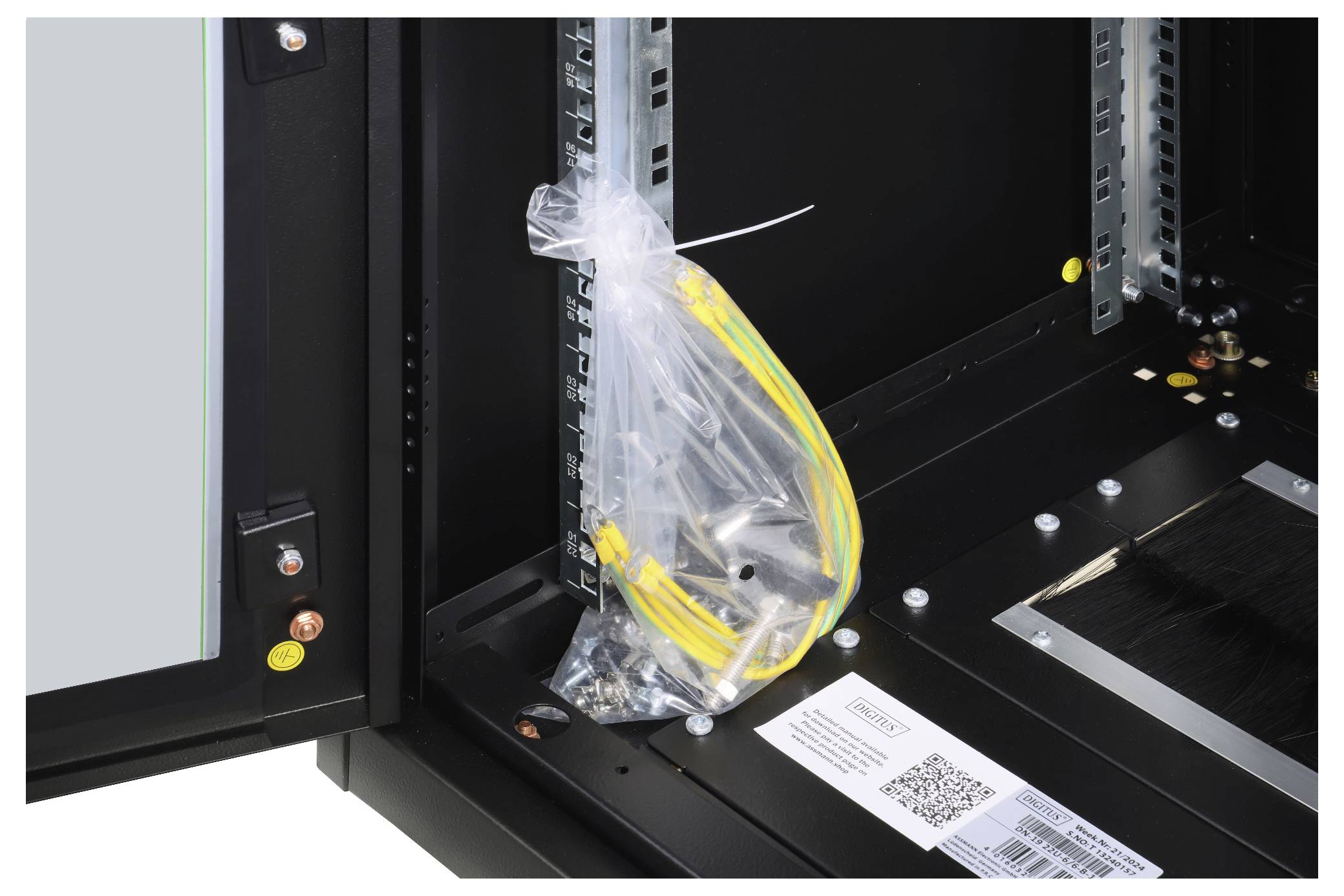 Ein Bündel gelber und grüner Kabel in einem transparenten Plastikbeutel, befestigt in einem offenen schwarzen Technikgehäuse.