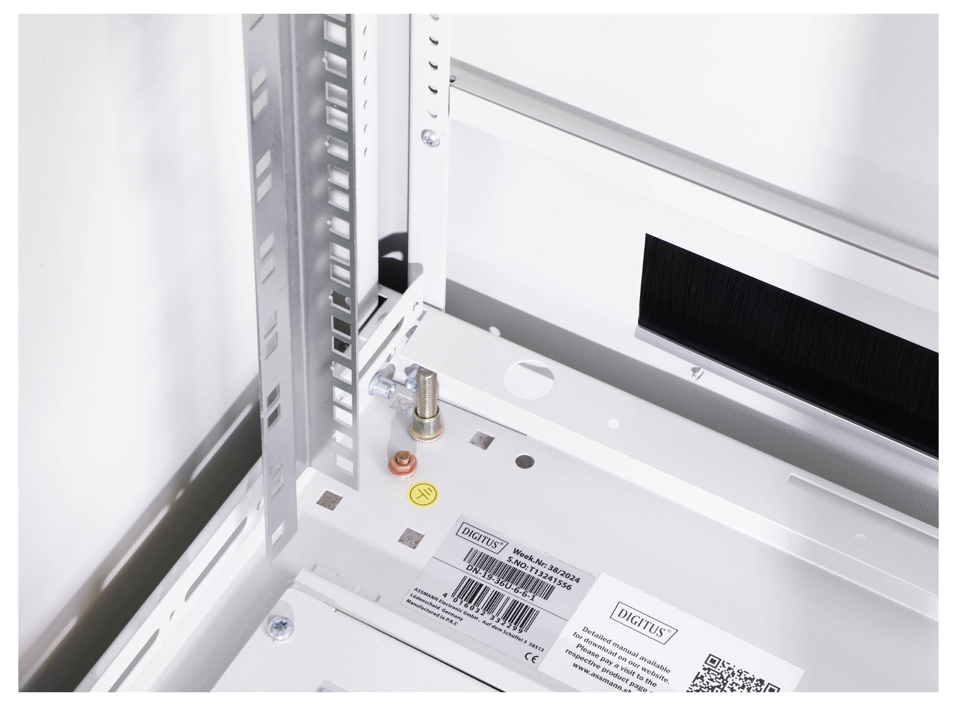 Innenansicht eines weißen technischen Gehäuses mit Metallrahmen und Befestigungselementen. Sichtbar sind Etiketten und Barcode.