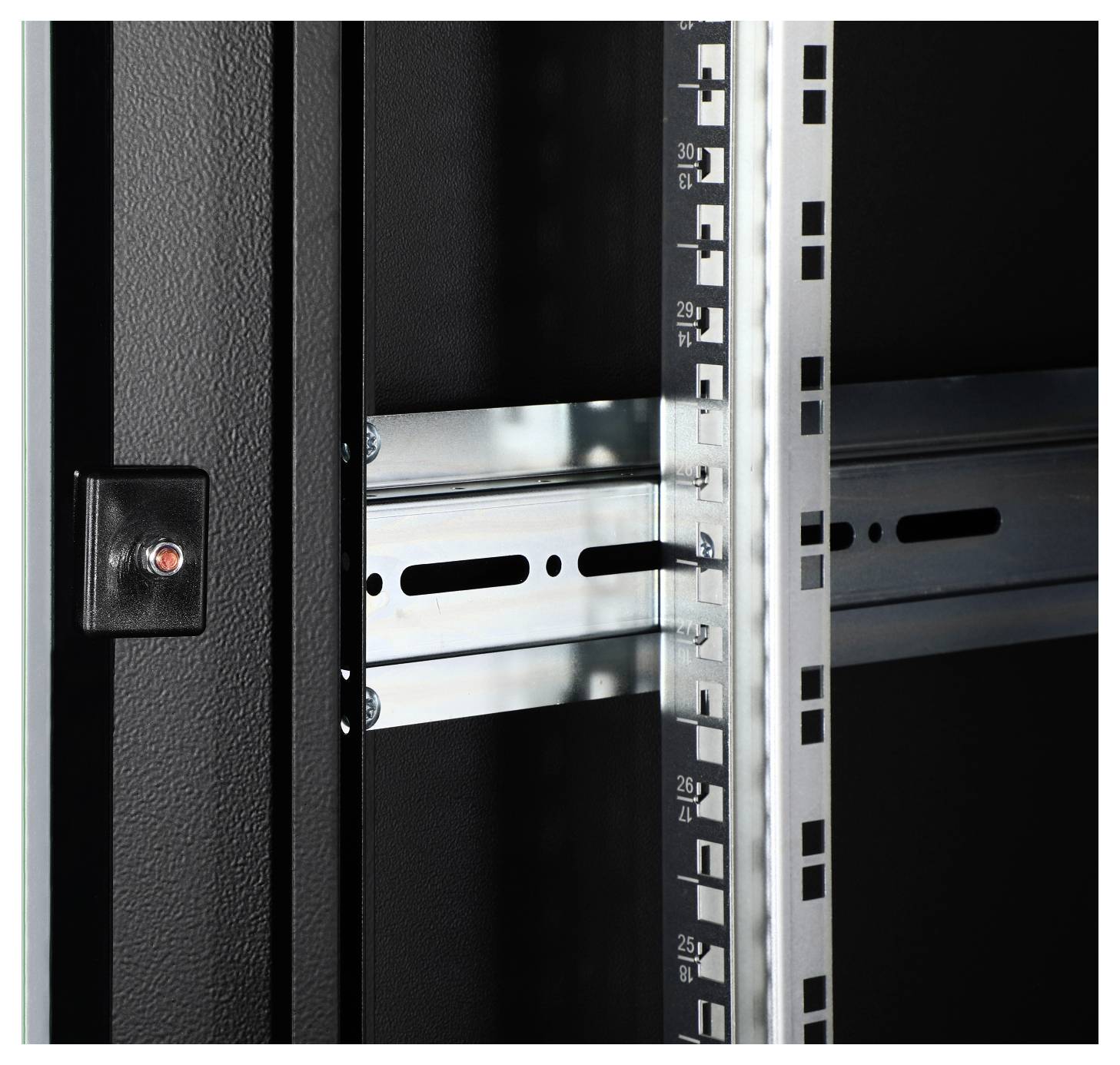 Nahaufnahme eines schwarzen Metallgehäuses mit Schienen und Zahlenmarkierungen, vermutlich für die Montage von elektronischen Geräten.
