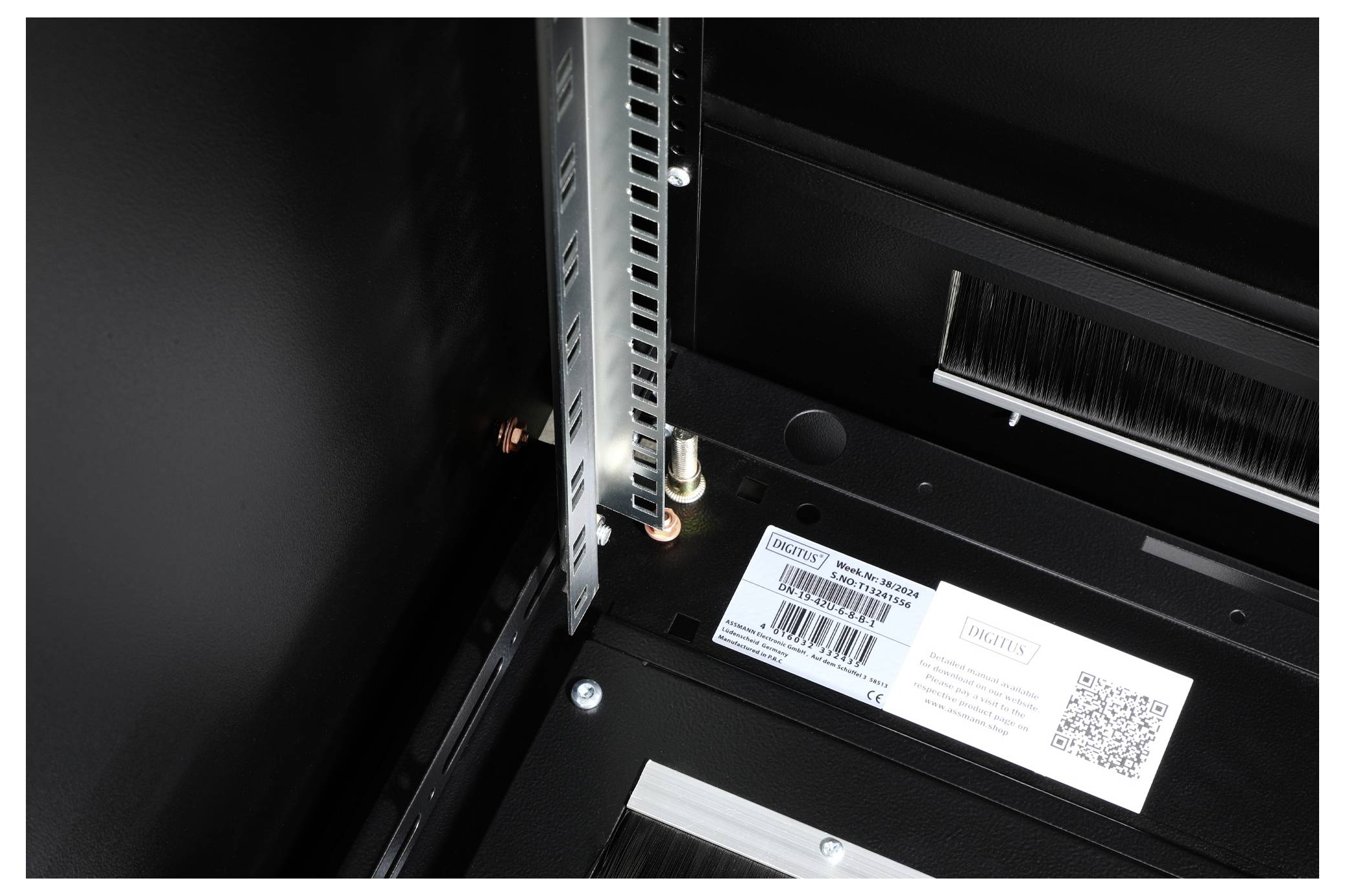 Innenansicht eines technischen Geräts mit sichtbarer Verkabelung und QR-Code-Etikett. Links oben ist ein Metallrahmen sichtbar.