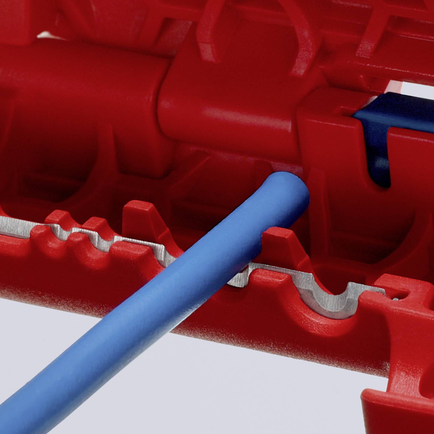 Ein blaues Kabel wird in eine rote Klemme eingesetzt, die Klemme hat gezackte Öffnungen zur sicheren Befestigung des Kabels.